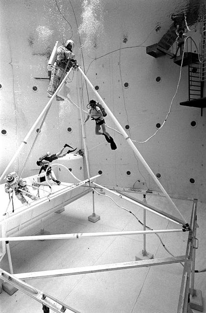 Once the United States' space program had progressed from Earth's orbit into outerspace, the prospect of building and maintaining a permanent presence in space was realized. To accomplish this feat, NASA launched a temporary workstation, Skylab, to discover the effects of low gravity and weightlessness on the human body, and also to develop tools and equipment that would be needed in the future to build and maintain a more permanent space station. The structures, techniques, and work schedules had to be carefully designed to fit this unique construction site. The components had to be lightweight for transport into orbit, yet durable. The station also had to be made with removable parts for easy servicing and repairs by astronauts. All of the tools necessary for service and repairs had to be designed for easy manipulation by a suited astronaut. And construction methods had to be efficient due to limited time the astronauts could remain outside their controlled environment. In lieu of all the specific needs for this project, an environment on Earth had to be developed that could simulate a low gravity atmosphere. A Neutral Buoyancy Simulator (NBS) was constructed by NASA Marshall Space Flight Center (MSFC) in 1968. Since then, NASA scientists have used this facility to understand how humans work best in low gravity and also provide information about the different kinds of structures that can be built. With the help of the NBS, building a space station became more of a reality. In a joint venture between NASA/Langley Research Center in Hampton, VA and MSFC, the Assembly Concept for Construction of Erectable Space Structures (ACCESS) was developed and demonstrated at MSFC's NBS. The primary objective of this experiment was to test the ACCESS structural assembly concept for suitability as the framework for larger space structures and to identify ways to improve the productivity of space construction. Pictured is a demonstration of ACCESS.