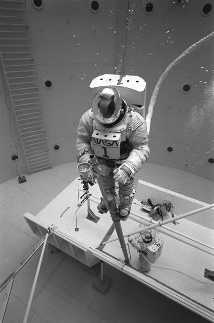 Once the United States' space program had progressed from Earth's orbit into outerspace, the prospect of building and maintaining a permanent presence in space was realized. To accomplish this feat, NASA launched a temporary workstation, Skylab, to discover the effects of low gravity and weightlessness on the human body, and also to develop tools and equipment that would be needed in the future to build and maintain a more permanent space station. The structures, techniques, and work schedules had to be carefully designed to fit this unique construction site. The components had to be lightweight for transport into orbit, yet durable. The station also had to be made with removable parts for easy servicing and repairs by astronauts. All of the tools necessary for service and repairs had to be designed for easy manipulation by a suited astronaut. Construction methods had to be efficient due to the limited time the astronauts could remain outside their controlled environment. In lieu of all the specific needs for this project, an environment on Earth had to be developed that could simulate a low gravity atmosphere. A Neutral Buoyancy Simulator (NBS) was constructed by NASA Marshall Space Flight Center (MSFC) in 1968. Since then, NASA scientists have used this facility to understand how humans work best in low gravity and also provide information about the different kinds of structures that can be built. With the help of the NBS, building a space station became more of a reality. In a joint venture between NASA/Langley Research Center in Hampton, Virginia and the MSFC, the Assembly Concept for Construction of Erectable Space Structures (ACCESS) was developed and demonstrated at MSFC's NBS. The primary objective of this experiment was to test the ACCESS structural assembly concept for suitability as the framework for larger space structures and to identify ways to improve the productivity of space construction. Pictured is a demonstration of ACCESS.