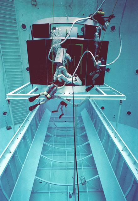 The Hubble Space Telescope (HST) is a cooperative program of the European Space Agency (ESA) and the National Aeronautical and Space Administration (NASA) to operate a long-lived space-based observatory; it was the flagship mission of NASA's Great Observatories program. The HST program began as an astronomical dream in the 1940s. During the 1970s and 1980s, HST was finally designed and built; and it finally became operational in the 1990s. HST was deployed into a low-Earth orbit on April 25, 1990 from the cargo bay of the Space Shuttle Discovery (STS-31). The design of the HST took into consideration its length of service and the necessity of repairs and equipment replacement by making the body modular. In doing so, subsequent shuttle missions could recover the HST, replace faulty or obsolete parts and be re-released. Pictured is MSFC's Neutral Buoyancy Simulator which served as the test center for shuttle astronauts training for Hubble related missions. Shown are astronauts McCandless and Nelson training on a mock-up of a modular section of the HST in removal/replacement of scientific instruments.