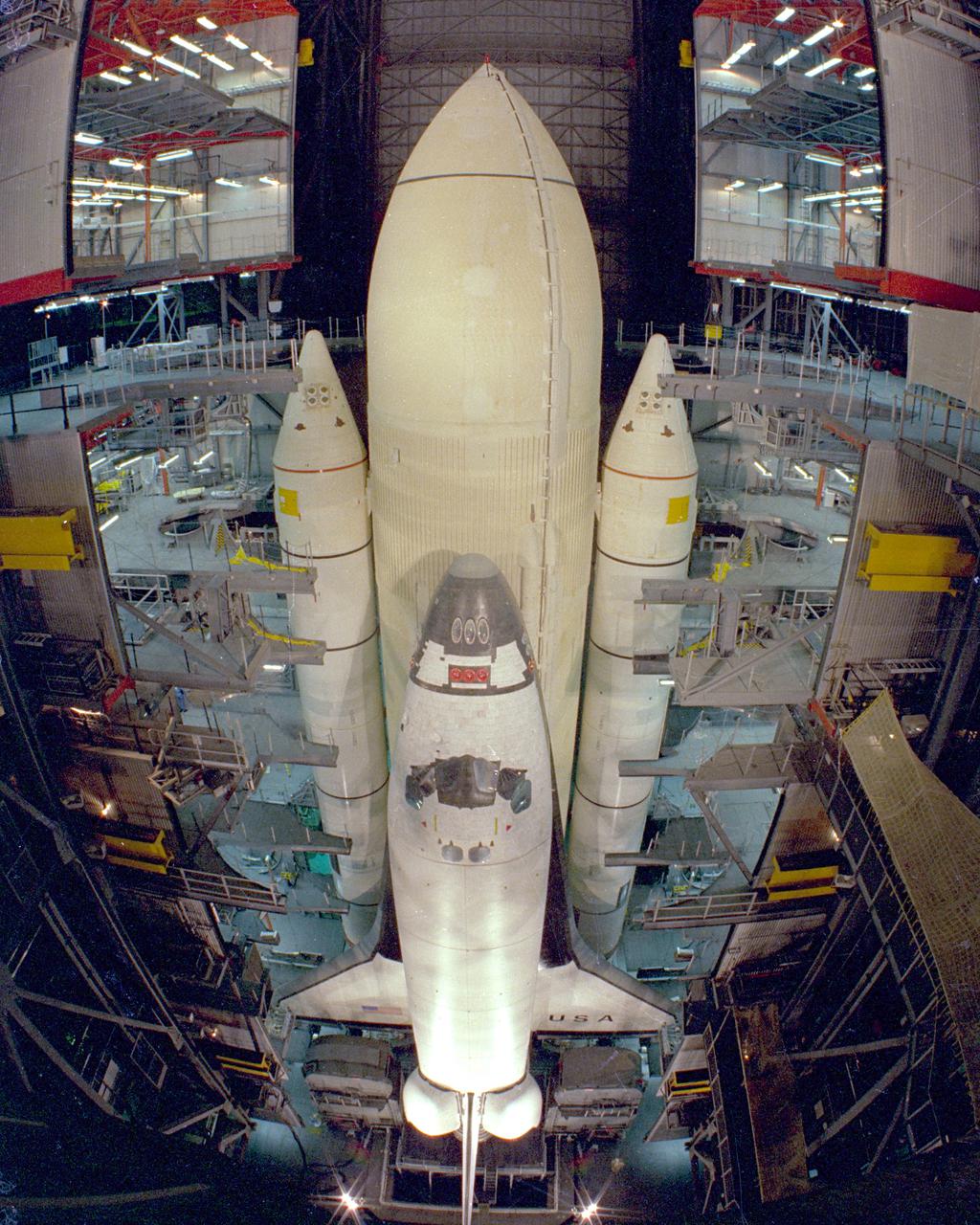 KENNEDY SPACE CENTER, FLA. - Assembly of the first Space Shuttle vehicle, scheduled to make its first orbital test flight in March 1981, was completed today with the mating of the Orbiter Columbia to its eternal tank in the Vehicle Assembly Building's High Bay 3. Columbia, shown here still attached to its hoisting sling, was moved to the VAB on Nov. 24 having completed tests and tile installation in the adjacent Orbiter Processing Facility. The other Shuttle components, the twin solid rocket boosters and the external propellant tank, were stacked on the Mobile launcher Platform in High Bay 3 in January and November of this year, respectively. The current schedule calls for the rollout of the assembled Space Shuttle to Pad A at Launch Complex 39 shortly after Christmas.