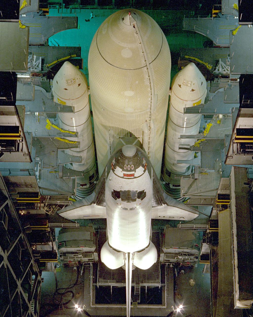 KENNEDY SPACE CENTER, FLA. - Assembly of the first Space Shuttle vehicle, scheduled to make its first orbital test flight in March 1981, was completed today with the mating of the Orbiter Columbia to its external tank in the Vehicle Assembly Building's High Bay 3. Columbia, shown here still attached to its hoisting sling, was moved to the VAB on Nov. 24 having completed tests and tile installation in the adjacent Orbiter Processing Facility. The other Shuttle components, the twin solid rocket boosters and the external propellant tank, were stacked on the Mobile Launcher Platform in High Bay 3 in January and November of this year, respectively. The current schedule calls for the rollout of the assembled Space Shuttle to Pad A at Launch Complex 39 shortly after Christmas.