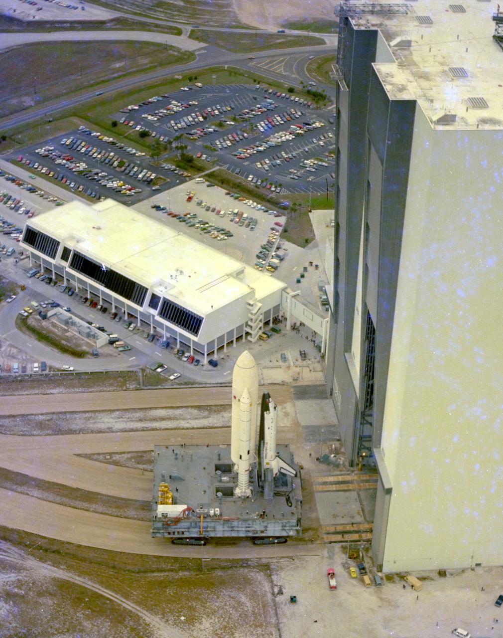 KENNEDY SPACE CENTER, FLA. -  This aerial view of STS-1 shows the space vehicle for the first Space Shuttle mission shortly after it was moved out of the Vehicle Assembly Builidng's High Bay 3 for the 3.5-mile journey to Pad A at Launch Complex 39.  In the center background is the Launch Control Center from which countdowns for Space Shuttle missions will be conducted.  The rollout to the pad took place little more than a month after the Space Shuttle Orbiter Columbia was rolled from the Orbiter Processing Facility to the VAB for mating on a Mobile Launcher Platform with the STS-1 external tank and solid rocket boosters.