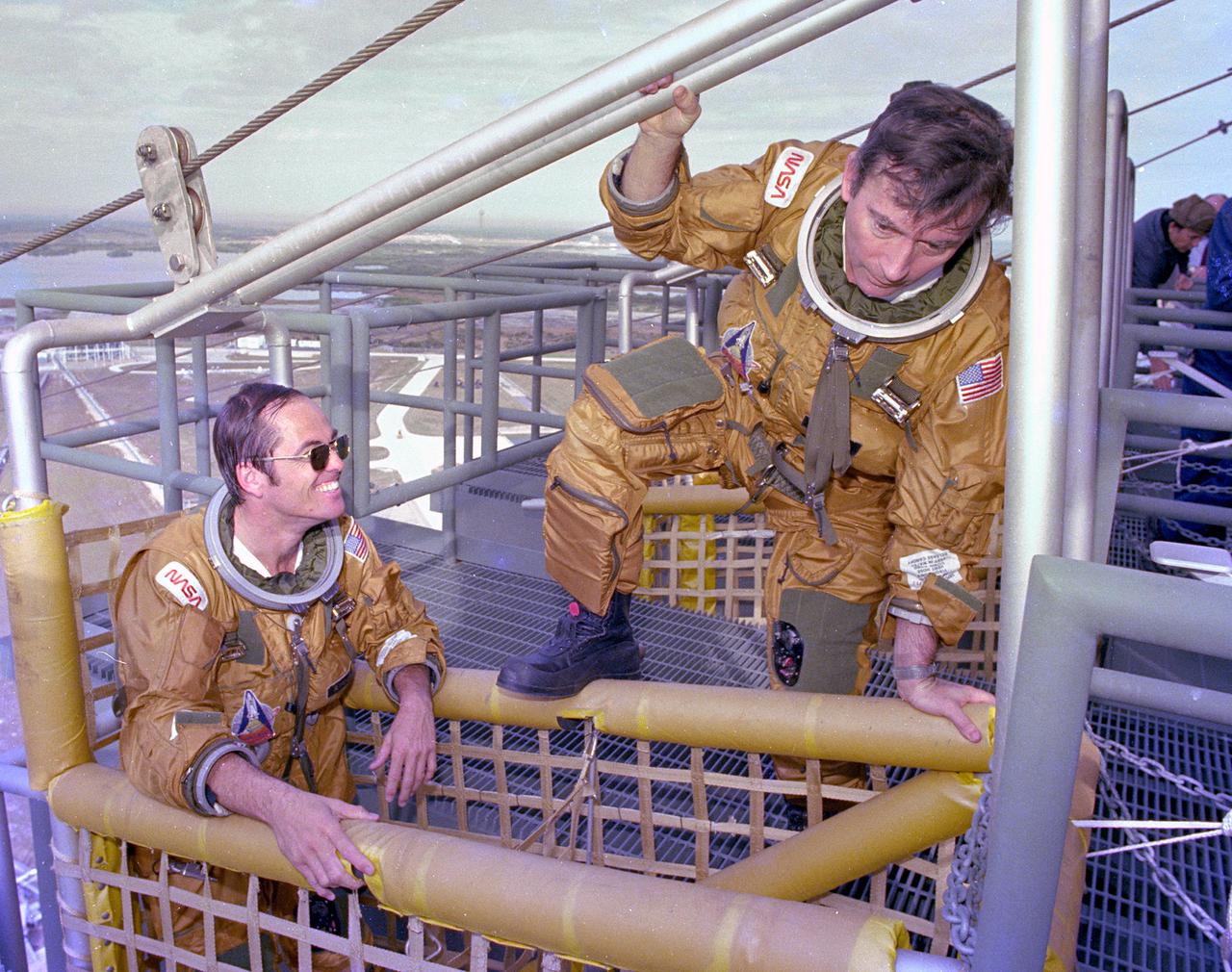 KENNEDY SPACE CENTER, FLA. -  Space Shuttle prime crew astronauts Bob Crippen (left) and John Young (center) board the emergency pad escape system known as the 'slidewire.'  The slidewire system provides a quick escape from upper launch pad platforms in case of a serious emergency.  The flight crews wore the spacesuits and other equipment to be worn during a mission, but sandbags were used to duplicate the weight of riders in the slidewire baskets during the training.
