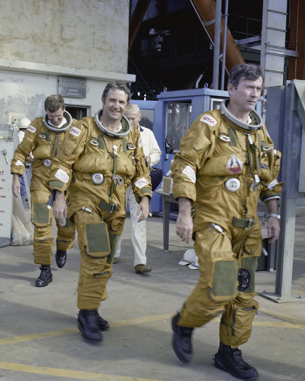 KENNEDY SPACE CENTER, FLA. - Space Shuttle prime and backup astronaut crews are preparing to be briefed on the use of the emergency pad escape system, known as the “slidewire”. From left to right are backup astronauts Joe Engle and Richard Truly, and primary crew Commander John Young. Both the prime and backup crews wore the spacesuits and other equipment they will wear during a mission. The slidewire system provides a quick and sure escape from the upper pad platforms in case of a serious emergency. The flight crews wore the spacesuits and other equipment to be worn during a mission, but sandbags were used to duplicate the weight of riders in the slidewire baskets during the training. The STS-1 mission, known as a shuttle systems test flight, will seek to demonstrate safe launch into orbit and safe return of the orbiter and crew and verify the combined performance of the entire shuttle vehicle -- orbiter, solid rocket boosters and external tank. STS-1 will be launched from Pad A at the Kennedy Space Center's Launch Complex 39 no earlier than March 1981.