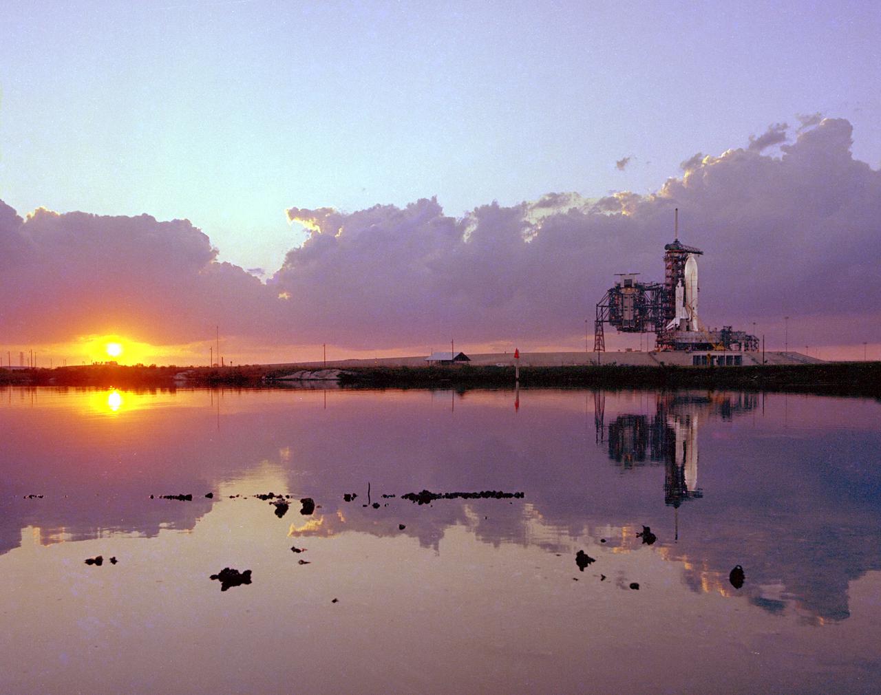 KENNEDY SPACE CENTER, FLA. -  Dramatically reflected by the waters of the extensive lagoonal sysem adjacent to Launch Pad A, the Space Shuttle, the world's first reusable space vehicle, is lighted by spotlights and the setting sun on the evening prior to Flight Readiness Firing of the orbiter Columbia's main engines.  The 20-second firing was a milestone procedure in flight preparation of the world's first reusable space vehicle.