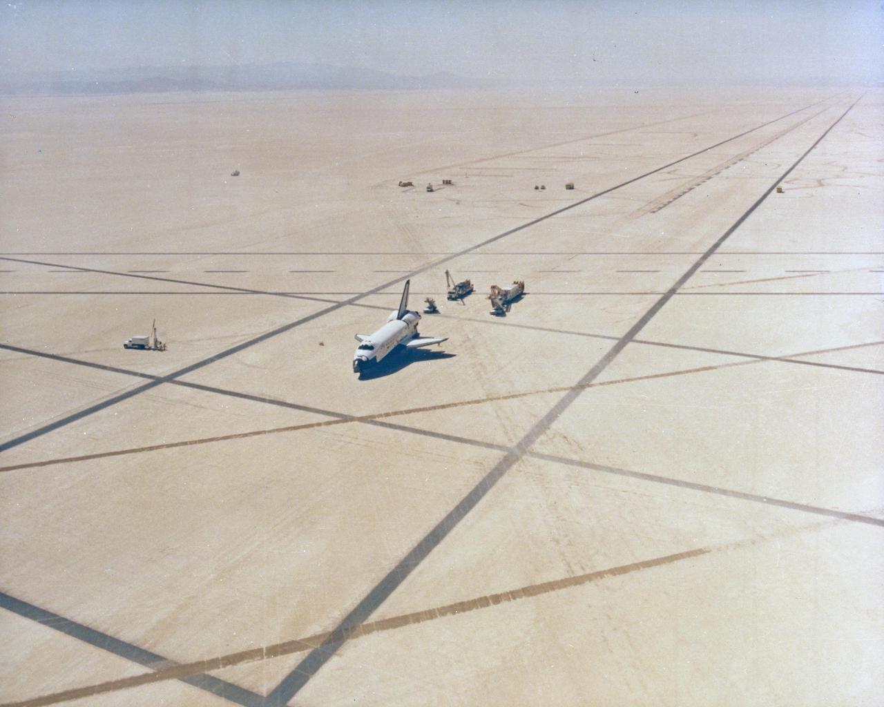 DRYDEN FLIGHT RESEARCH CENTER, CALIF.  -   Columbia returns to Earth after completing the first full test of the Space Transportation System (STS-1).  The orbiter Columbia is seen here on the Rogers dry lake, Runway 23, at NASA's Dryden Flight Research Center, Edwards, California.  From this aerial view, the orbiter Columbia is seen as it is being convoyed to a parking area.  For this first flight, the Columbia was flown by Astronauts John Young, commander, and Robert Crippen, pilot. STS-1, known as a shuttle systems test flight, sought to demonstrate safe launch into orbit and safe return of the orbiter and crew and verify the combined performance of the entire shuttle vehicle -- orbiter, solid rocket boosters and external tank.