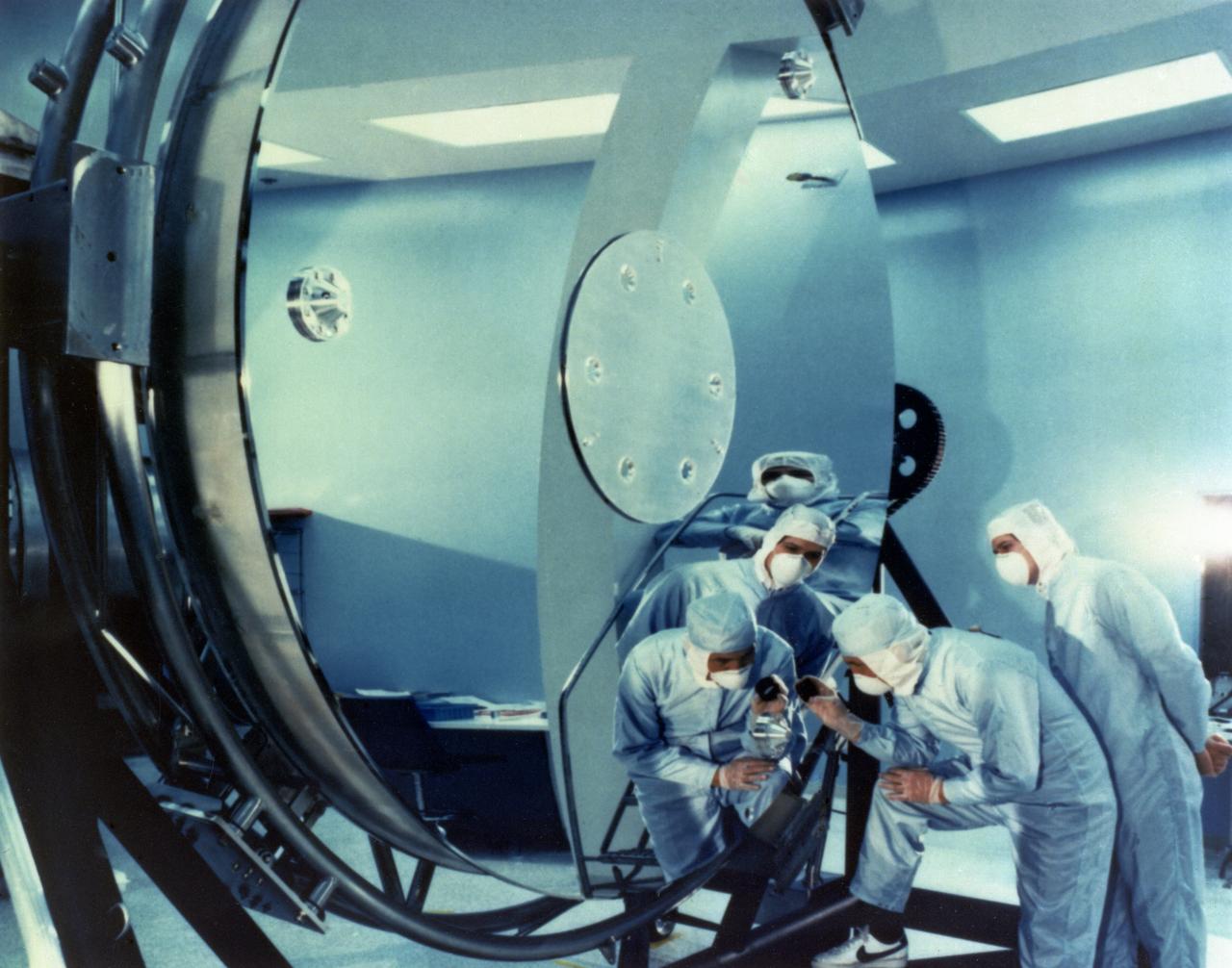 Prior to installation, technicians inspect the primary mirror of the Hubble Space Telescope (HST). The first in a series of great observatories launched by NASA, the HST was designed to last approximately 15 years. The Marshall Space Flight Center had management responsibility for the development of the HST and played a major role in ground tests and orbital checkout of the telescope. The HST was launched April 24, 1990 aboard Space Shuttle Discovery's STS-31 mission.