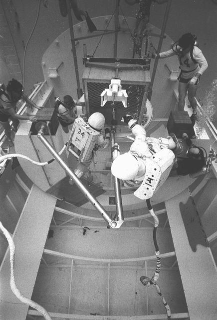 In February 1980, a satellite called Solar Maximum Mission Spacecraft, or Solar Max, was launched into Earth's orbit. Its primary objective was to provide a detailed study of solar flares, active regions on the Sun's surface, sunspots, and other solar activities. Additionally, it was to measure the total output of radiation from the Sun. Not much was known about solar activity at that time except for a slight knowledge of solar flares. After its launch, Solar Max fulfilled everyone's expectations. However, after a year in orbit, Solar Max's Altitude Control System malfunctioned, preventing the precise pointing of instruments at the Sun. NASA scientists were disappointed at the lost data, but not altogether dismayed because Solar Max had been designed for Space Shuttle retrievability enabling the repair of the satellite. On April 6, 1984, Space Shuttle Challenger (STS-41C), Commanded by astronaut Robert L. Crippen and piloted by Francis R. Scobee, launched on a historic voyage. This voyage initiated a series of firsts for NASA; the first satellite retrieval, the first service use of a new space system called the Marned Maneuvering Unit (MMU), the first in-orbit repair, the first use of the Remote Manipulator System (RMS), and the Space Shuttle Challenger's first space flight. The mission was successful in retrieving Solar Max. Mission Specialist Dr. George D. Nelson, using the MMU, left the orbiter's cargo bay and rendezvoused with Solar Max. After attaching himself to the satellite, he awaited the orbiter to maneuver itself nearby. Using the RMS, Solar Max was captured and docked in the cargo bay while Dr. Nelson replaced the altitude control system and the coronagraph/polarimeter electronics box. After the repairs were completed, Solar Max was redeposited in orbit with the assistance of the RMS. Prior to the April 1984 launch, countless man-hours were spent preparing for this mission. The crew of Challenger spent months at Marshall Space Flight Center's (MSFC) Neutral Buoyancy Simulator (NBS) practicing retrieval maneuvers, piloting the MMU, and training on equipment so they could make the needed repairs to Solar Max. Pictured are crew members training on repair tasks.