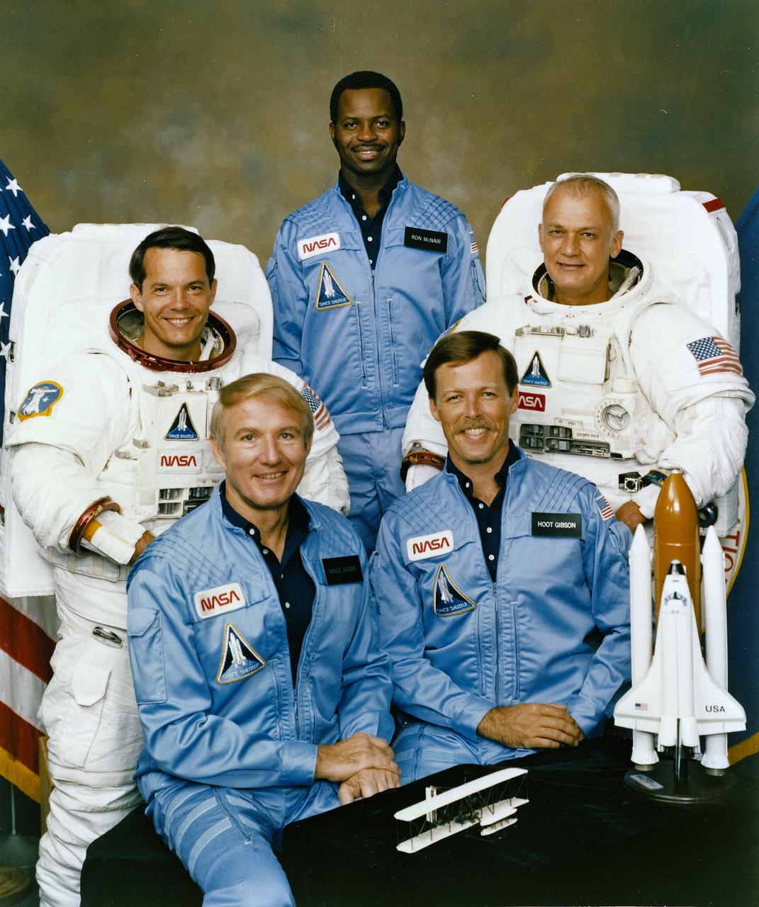 The crew assigned to the STS-41B (STS-11) mission included (seated left to right) Vance D. Brand, commander; and Robert L. Gibson, pilot. Standing left to right are mission specialists Robert L. Stewart, Ronald E. McNair, and Bruce McCandless. Launched aboard the Space Shuttle Challenger on February 3, 1984 at 8:00:00 am (EST), the STS-41B mission marked the first untethered space walks which were performed by McCandless and Stewart.  The crew  deployed the WESTAR-VI and PALAPA-B2 satellites.