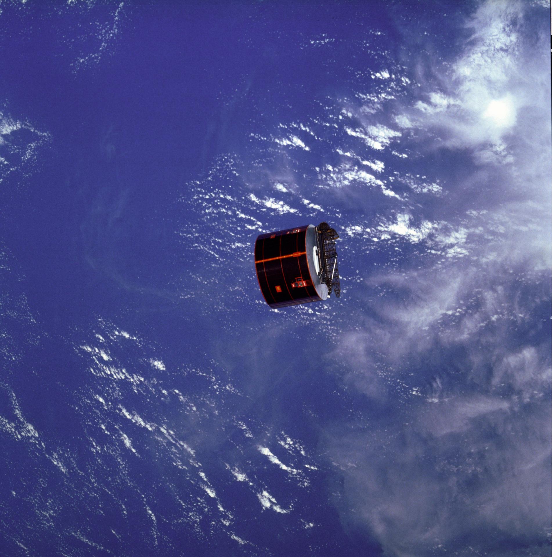 The SYNCOM IV-3 satellite is viewed from above the Earth's oceans and clouds from Space Shuttle Discovery.