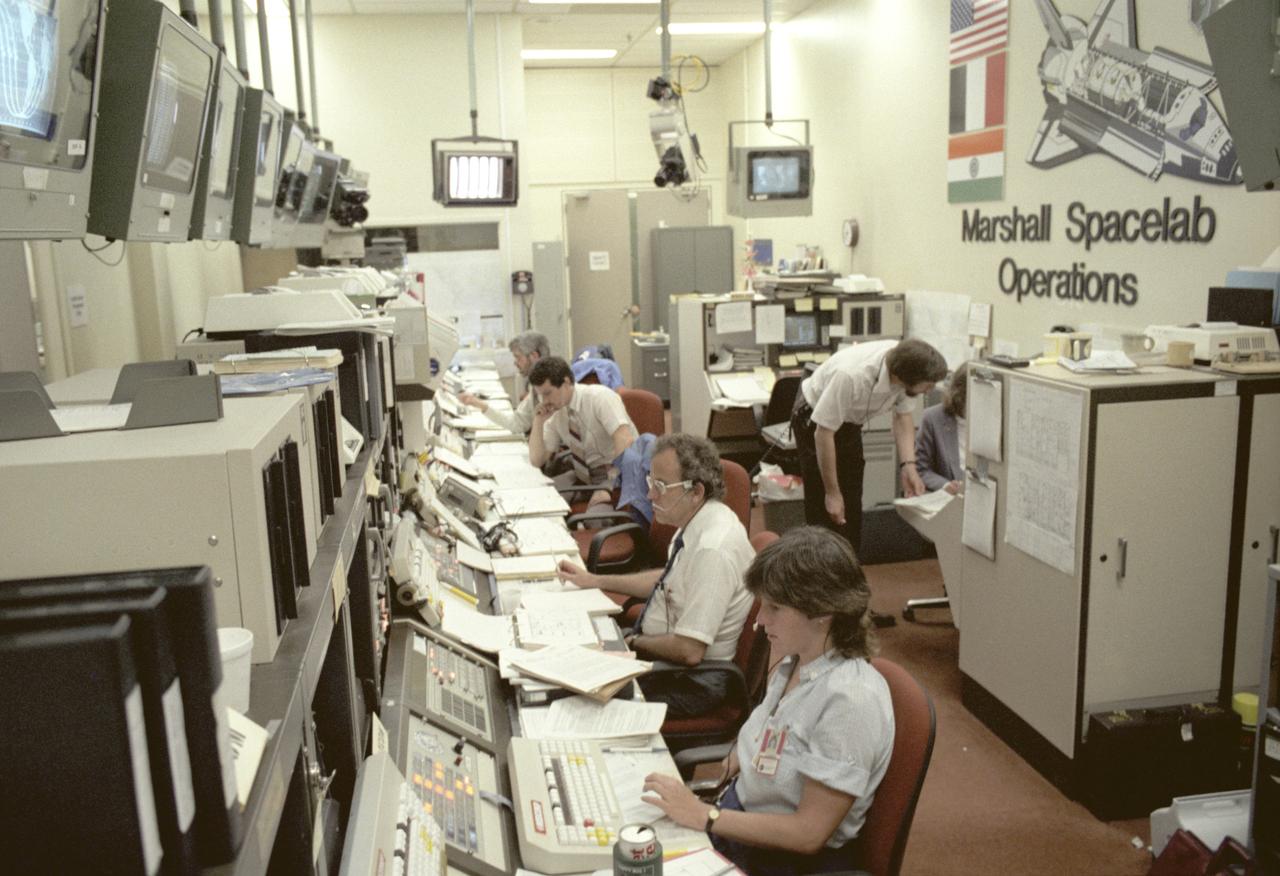 Spacelab-3 launched aboard STS-51B, with the major science objective being to perform engineering tests on two new facilities: the rodent animal holding facility and the primate animal holding facility. In addition, scientists observed the animals to obtain first hand knowledge of the effects of launch and reentry stresses and behavior. The need for suitable animal housing to support research in space led to the development of the Research Animal Holding Facility at the Ames Research Center. Scientists often study animals to find clues to human physiology and behavior. Rats, insects, and microorganisms had already been studied aboard the Shuttle on previous missions. On Spacelab-3, scientists had a chance to observe a large number of animals living in space in a specially designed and independently controlled housing facility. Marshall Space Flight Center (MSFC) had management responsibility for the Spacelab-3 mission. This photograph depicts activities during the mission at the Huntsville Operations Support Center (HOSC) Spacelab Payload Operations Control Center (SL POCC) at MSFC.