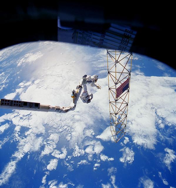 This is an STS-61B onboard photo of astronauts Ross and Spring on the Remote Manipulator System (RMS) as they approach the erected Assembly Concept for Construction of Erectable Space Structure (ACCESS).