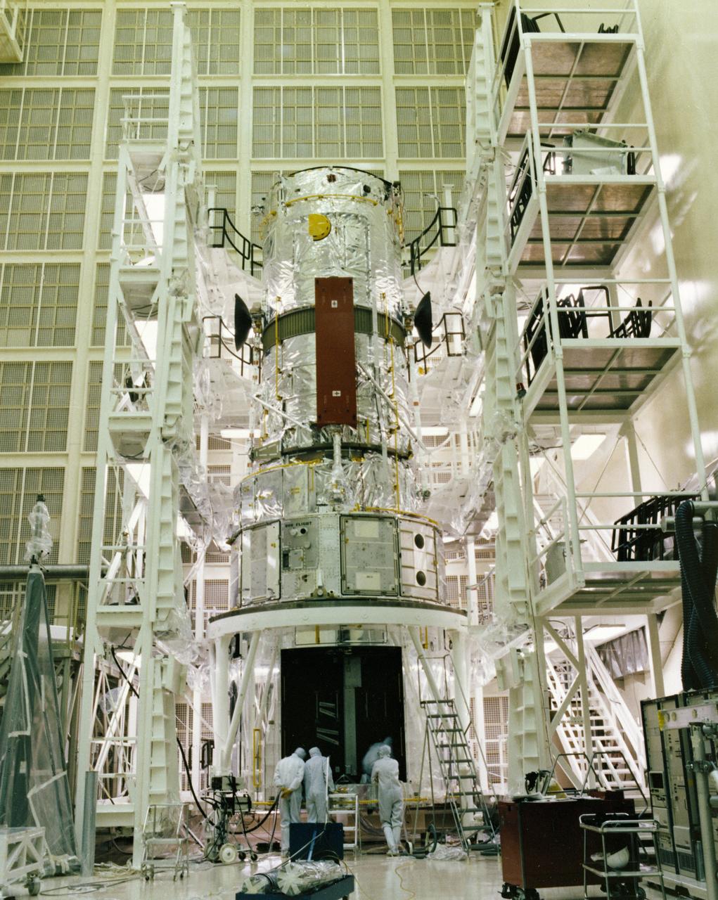 This photograph shows the Hubble Space Telescope (HST) flight article assembly with multilayer insulation, high gain anterna, and solar arrays in a clean room of the Lockheed Missile and Space Company. The HST is the first of NASA's great observatories and the most complex and sensitive optical telescope ever made. The purpose of the HST is to study the cosmos from a low-Earth orbit by placing the telescope in space, enabling astronomers to collect data that is free of the Earth's atmosphere. The HST was deployed from the Space Shuttle Discovery (STS-31 mission) into Earth orbit in April 1990. The Marshall Space Flight Center had overall responsibility for design, development, and construction of the HST. The Perkin-Elmer Corporation, in Danbury, Connecticut, developed the optical system and guidance sensors. The Lockheed Missile and Space Company, Sunnyvale, California, produced the protective outer shroud and spacecraft systems, and assembled and tested the finished telescope.