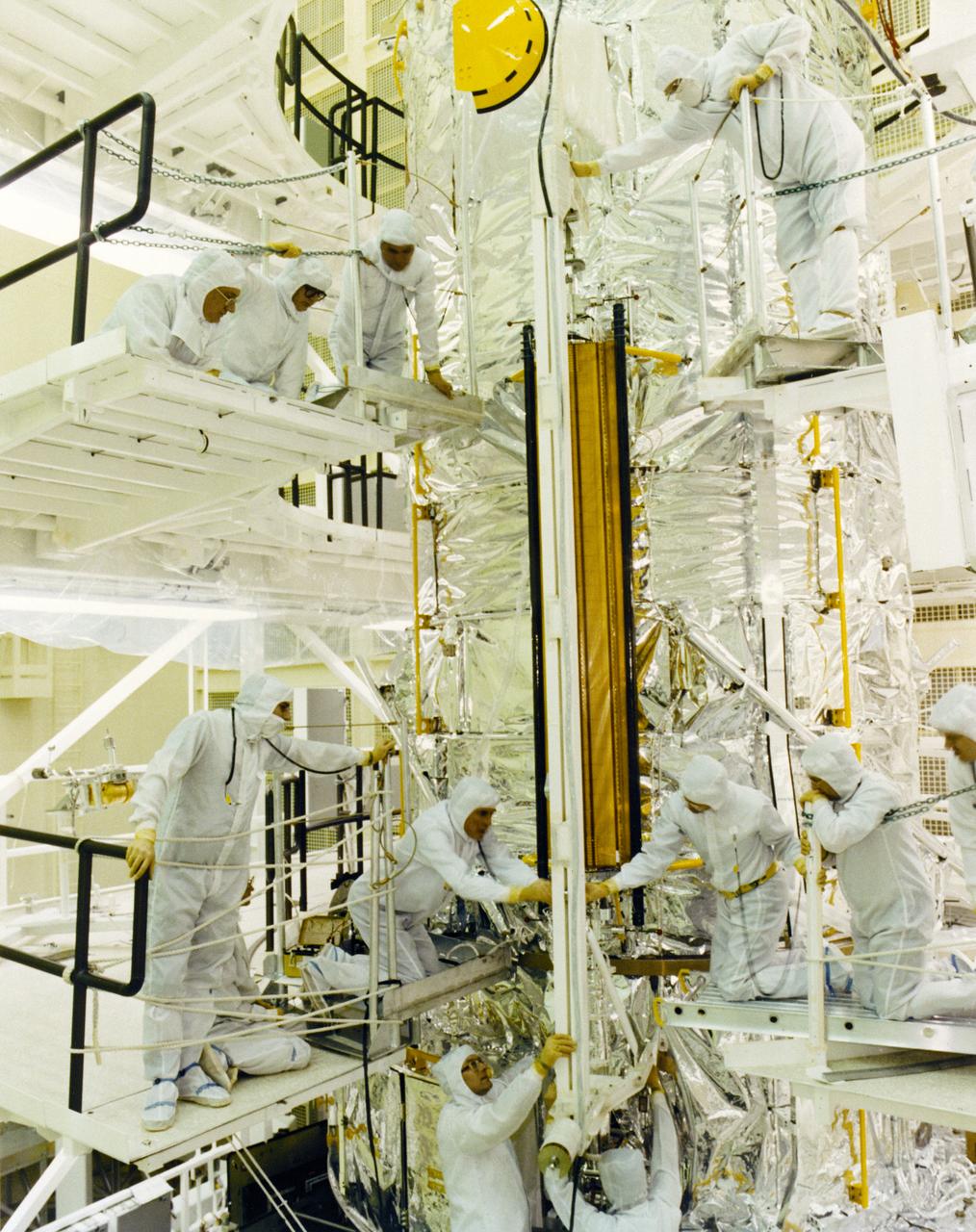 Engineers and technicians conduct a fit check of the Hubble Space Telescope (HST) Solar Array flight article in a clean room of the Lockheed Missile and Space Company. The Solar Array is 40- feet (12.1-meters) long and 8.2-feet (2.5-meters) wide, and provides power to the spacecraft. The HST is the first of NASA's great observatories and the most complex and sensitive optical telescope ever made. The purpose of the HST is to study the cosmos from a low-Earth orbit by placing the telescope in space, enabling astronomers to collect data that is free of the Earth's atmosphere. The HST was deployed from the Space Shuttle Discovery (STS-31 mission) into Earth orbit in April 1990. The Marshall Space Flight Center had overall responsibility for design, development, and construction of the HST. The Perkin-Elmer Corporation, in Danbury, Cornecticut, developed the optical system and guidance sensors. The Lockheed Missile and Space Company, Sunnyvale, California, produced the protective outer shroud and spacecraft systems, and assembled and tested the finished telescope.