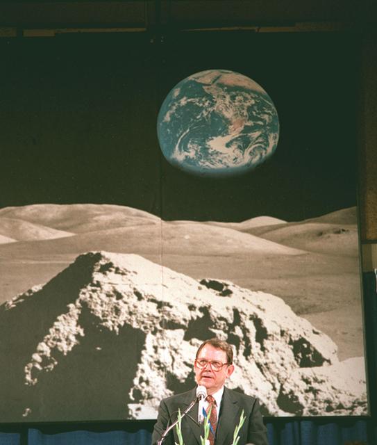 Dr. William R. Lucas, Marshall's fourth Center Director (1974-1986), delivers a speech in front of a picture of the lunar landscape with Earth looming in the background while attending a Huntsville Chamber of Commerce reception honoring his achievements as Director of Marshall Space Flight Center (MSFC).