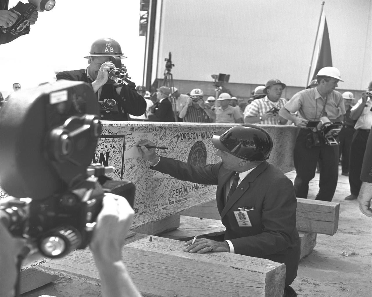 KENNEDY SPACE CENTER, FLA. -- Dr. Kurt Debus, Kennedy Space Center's first director, adds his name to the thousands of signatures affixed to the 38-foot-long steel beam used in the VAB's 'Topping Off' ceremonies.