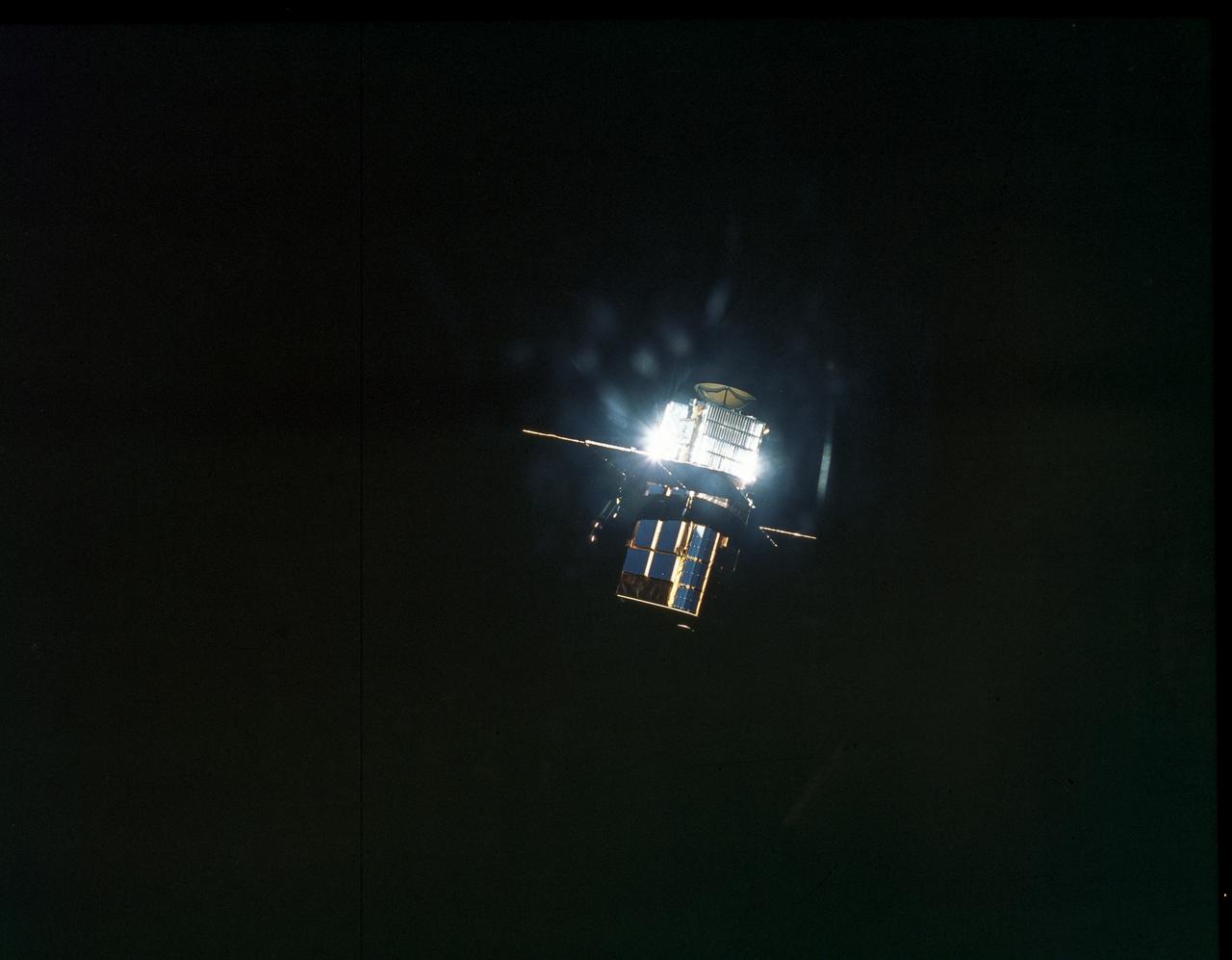 This is a photograph of the free-flying Solar Maximum Mission Satellite (SMMS), or Solar Max, as seen by the approaching Space Shuttle Orbiter Challenger STS-41C mission. Launched April 6, 1984, one of the goals of the STS-41C mission was to repair the damaged Solar Max. The original plan was to make an excursion out to the SMMS for capture to make necessary repairs, however, this attempted feat was unsuccessful. It was necessary to capture the satellite via the orbiter's Remote Manipulator System (RMS) and secure it into the cargo bay in order to perform the repairs, which included replacing the altitude control system and the coronograph/polarimeter electronics box. The SMMS was originally launched into space via the Delta Rocket in February 1980, with the purpose to provide a means of studying solar flares during the most active part of the current sunspot cycle. Dr. Einar Tandberg-Hanssen of Marshall Space Flight Center's Space Sciences Lab was principal investigator for the Ultraviolet Spectrometer and Polarimeter, one of the seven experiments on the Solar Max.