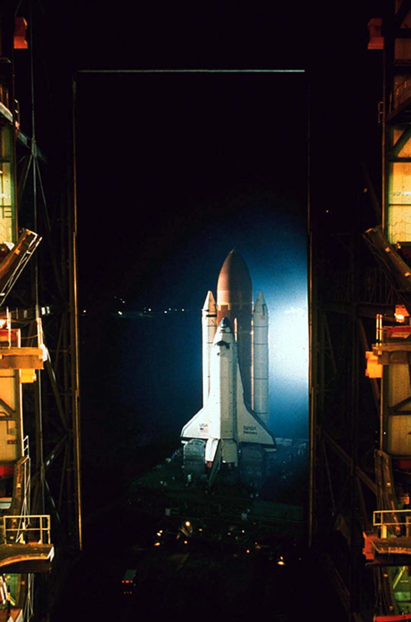 KENNEDY SPACE CENTER, FLA. -- A view from inside bay three of the Vehicle Assembly Building (VAB) shows the Space Shuttle Discovery washed in white  xenon light as it makes a nighttime departure from the VAB on its way to pad 39B. Discovery will fly for mission STS-26 now scheduled for launch in earlly September with its five-man crew and the TDRS-C payload. First motion in the Shuttle's move from the VAB toward the pad came at 12:50 a.m. July 4, 1988.