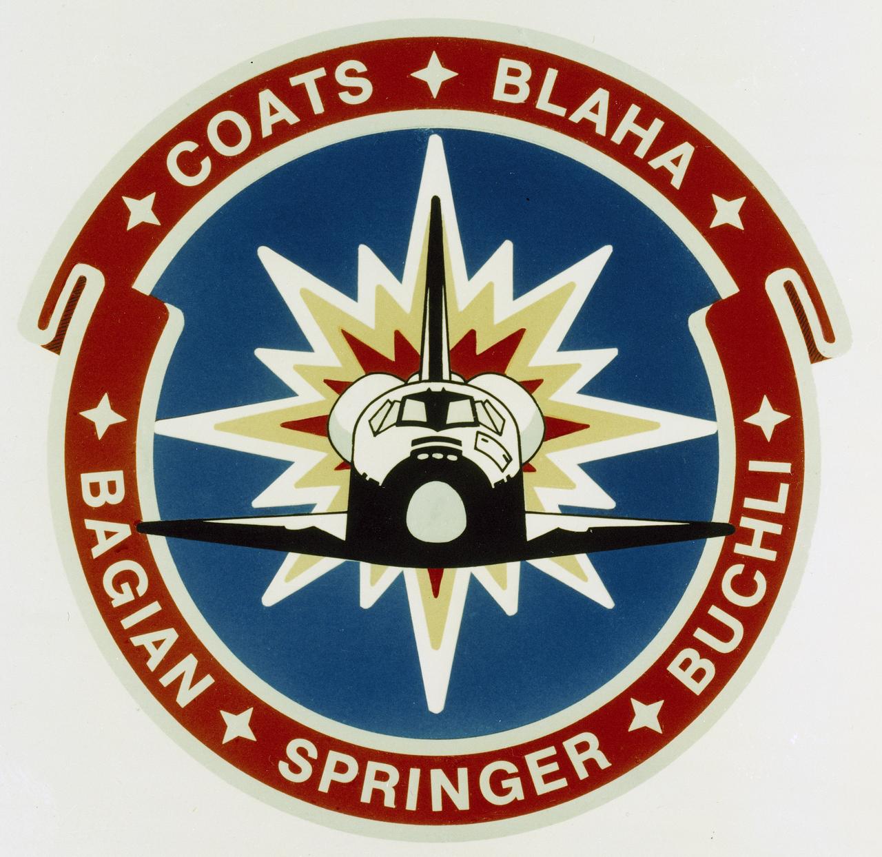 The STS-29 patch was designed to capture and represent the energy and dynamic nature of this nation's space program as America continues to look to the future. The folded ribbon border, the first of its kind in the Shuttle patch series, gives a sense of three dimensional depth to the emblem. The stylistic orbital maneuvering system (ONS) burn symbolizes the powerful forward momentum of the Shuttle and a continuing determination to explore the frontiers of space. The colors of the U.S. flag are represented in the patch's basic red, white, and blue background. In the border, the seven stars between the STS-29 crew names are a tribute to the crew of Challenger. 