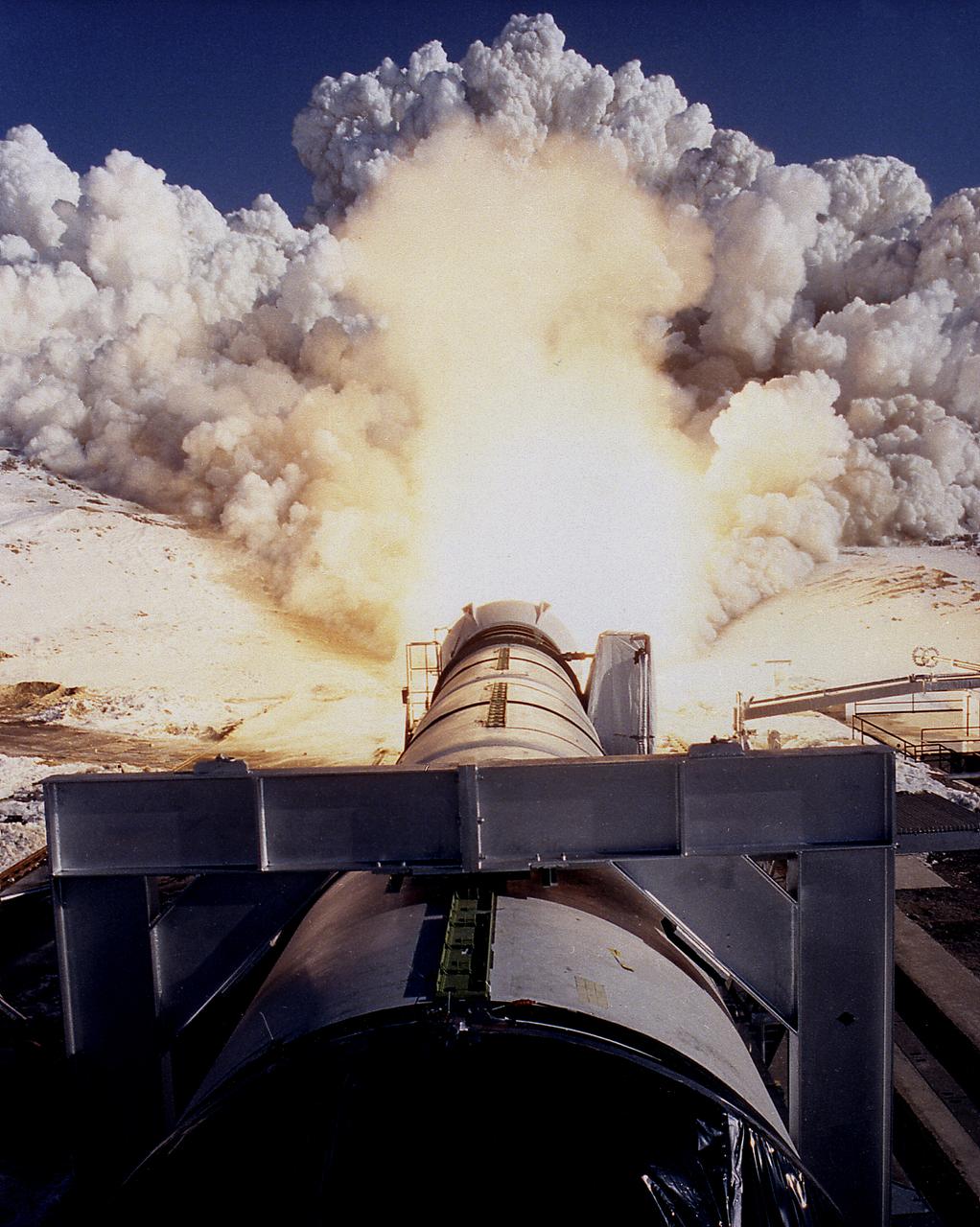 This photograph shows a static firing test of the Solid Rocket Qualification Motor-8 (QM-8) at the Morton Thiokol Test Site in Wasatch, Utah. The twin solid rocket boosters provide the majority of thrust for the first two minutes of flight, about 5.8 million pounds, augmenting the Shuttle's main propulsion system during liftoff. The major design drivers for the solid rocket motors (SRM's) were high thrust and reuse. The desired thrust was achieved by using state-of-the-art solid propellant and by using a long cylindrical motor with a specific core design that allows the propellant to burn in a carefully controlled marner. Under the direction of the Marshall Space Flight Center, the SRM's are provided by the Morton Thiokol Corporation.