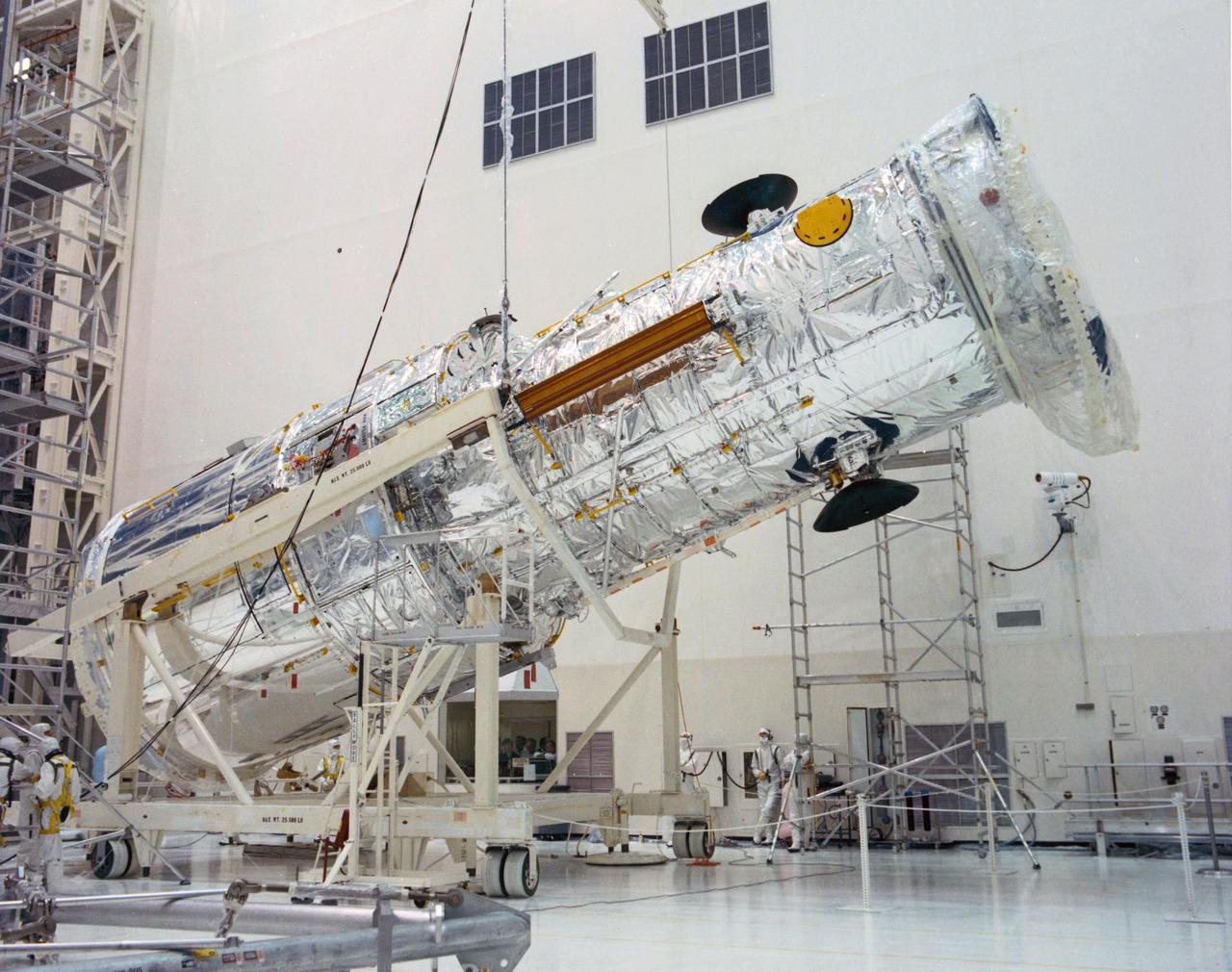 KENNEDY SPACE CENTER, FLA. -- The Hubble Space Telescope (HST) is lifted into the vertical position in the Vertical Processing Facility as work begins at KSC to process the 94-inch primary mirror telescope for launch on Discovery on Space Shuttle Mission STS-31 in March 1990. With HST, astronomers will be able to view 97 percent of the known universe, and will be able to get pictures unlimited and undistorted by the Earth's atmosphere. Compared with earth-based observatories, the HST will be able to view celestial objects that are 50 times fainter, provide images that are 10 times sharper, and see objects that are seven times farther away. .