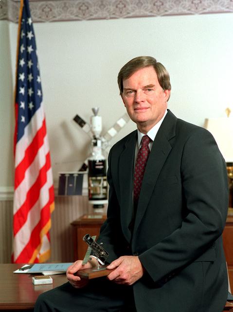 Informal executive portrait of Marshall's sixth Center Director Thomas J. Lee (1989-1994) holding a model of the Hubble Space Telescope (HST).