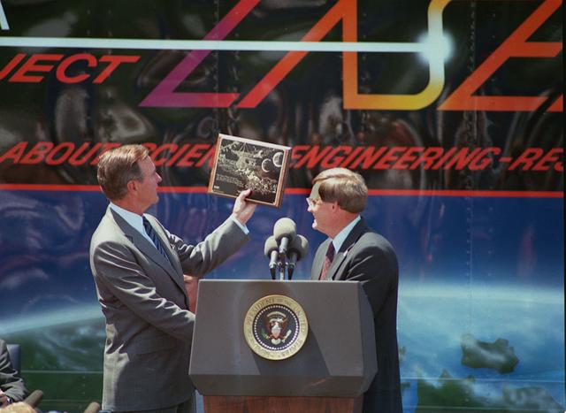 President George Bush receives a placque commemorating the quincentenary of Columbus' voyage to the new world and exploration from Marshall's sixth Center Director Thomas J. Lee (1989-1994) during an address to Marshall employees. The three replicas of Columbus' ships, the Nina, the Pinta, and the Santa Maria sailed by the launch pad at Kennedy Space Center while STS-52 Columbia awaited launch on the anniversary of Columbus' arrival in the New World.
