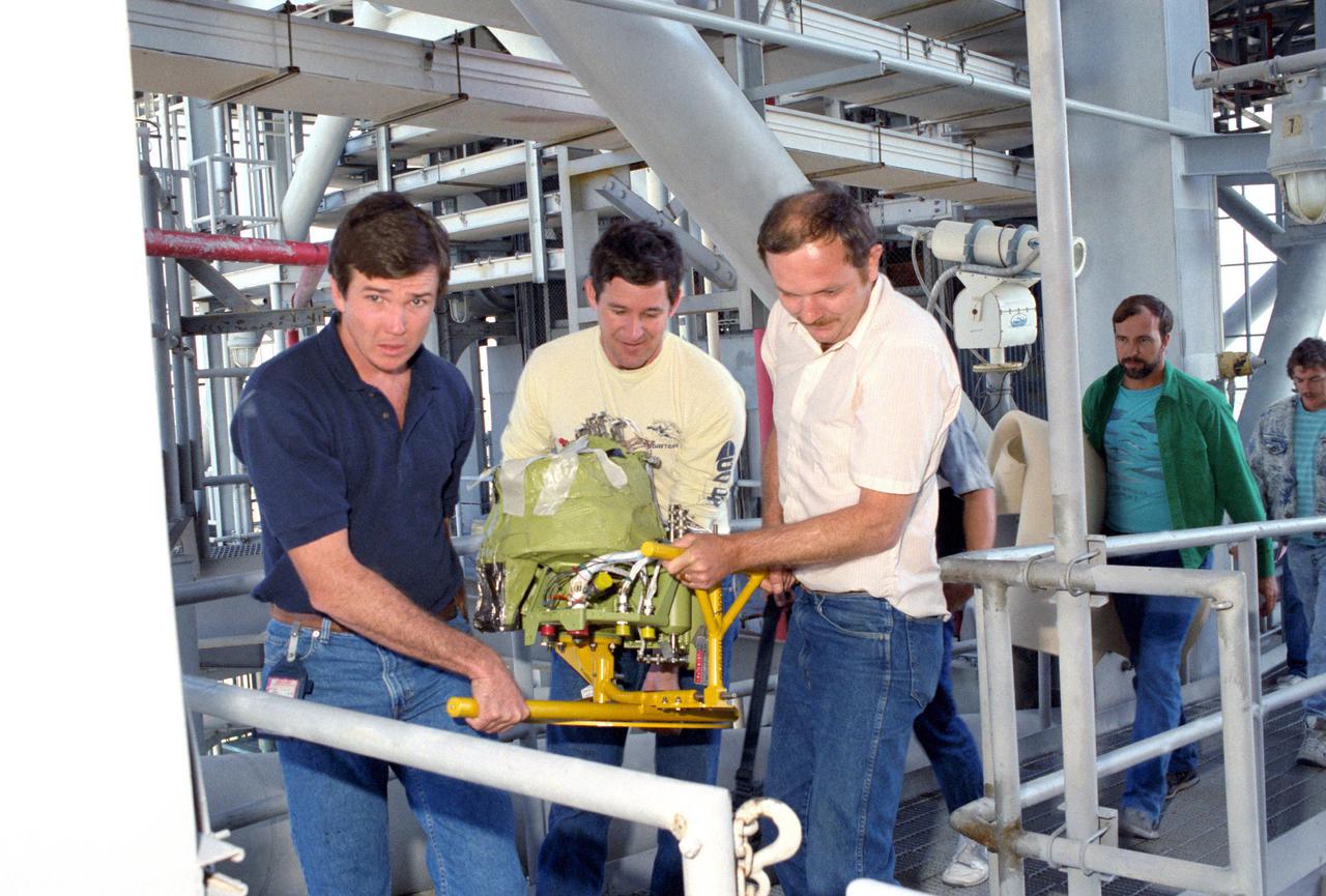 KENNEDY SPACE CENTER, FLA. -- Technicians at Pad 39-B carry a new Auxiliary Power Unit (APU) to be installed in the orbiter Discovery. It will replace APU #1 that failed during the STS-31 launch attempt on April 10.