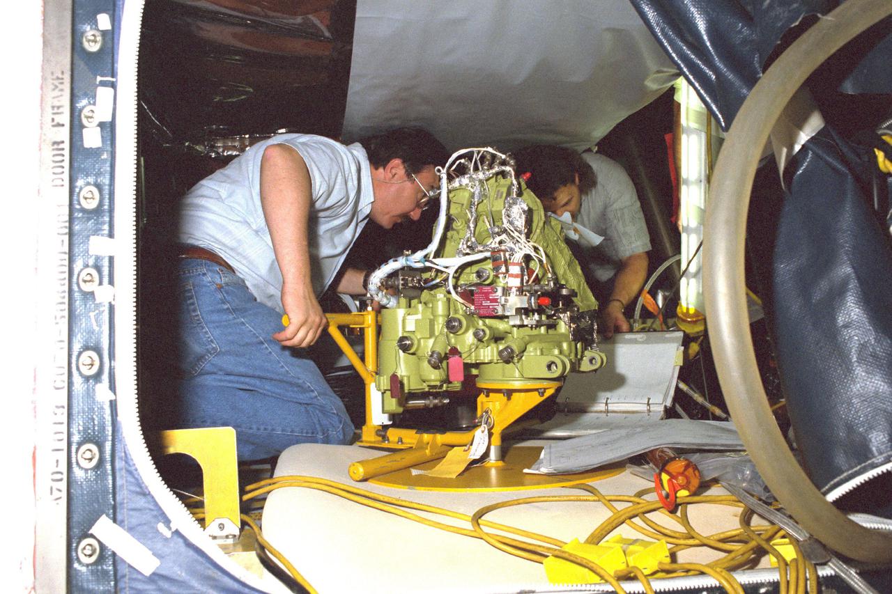 KENNEDY SPACE CENTER, FLA. -- Technicians install a new Auxiliary Power Unit (APU) in the aft compartment of the orbiter Discovery at Pad 39-B. The unit replaces APU #1 that failed during the STS-31 countdown on April 10.
