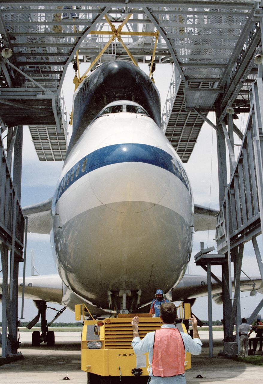 CAPE CANAVERAL, Fla. -- Space shuttle mission STS-31 comes full circle as the orbiter Discovery returns to KSC atop the shuttle carrier aircraft. Coaxing the duo into the mate_demate device at the SLF are John Goleno, driving the towing vehicle, and directing him, Peter Seidel. Photo credit: NASA