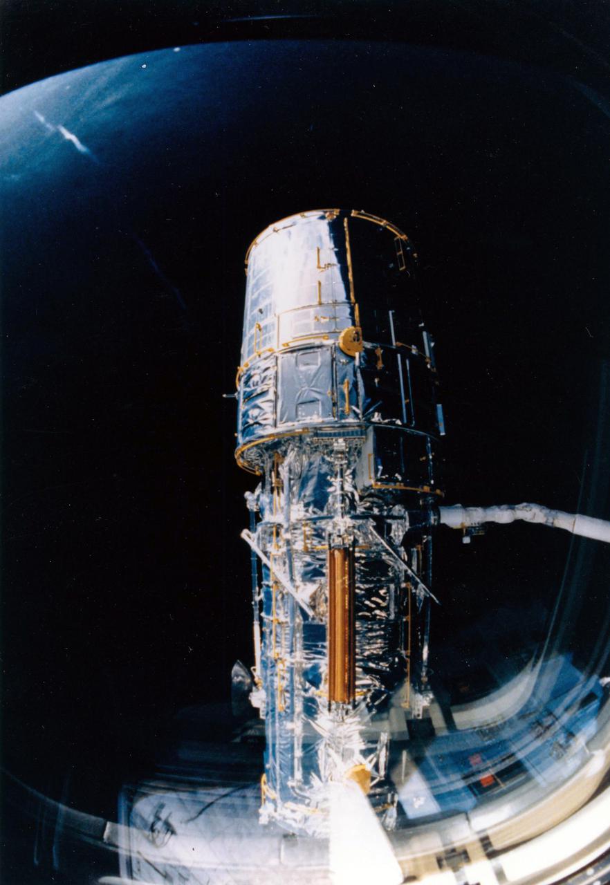 JOHNSON SPACE CENTER, HOUSTON, TEXAS -- View through overhead windows shows remote manipulator system (RMS) arm with telescope in grasp before procedures start to deploy solar array panels and antennae.