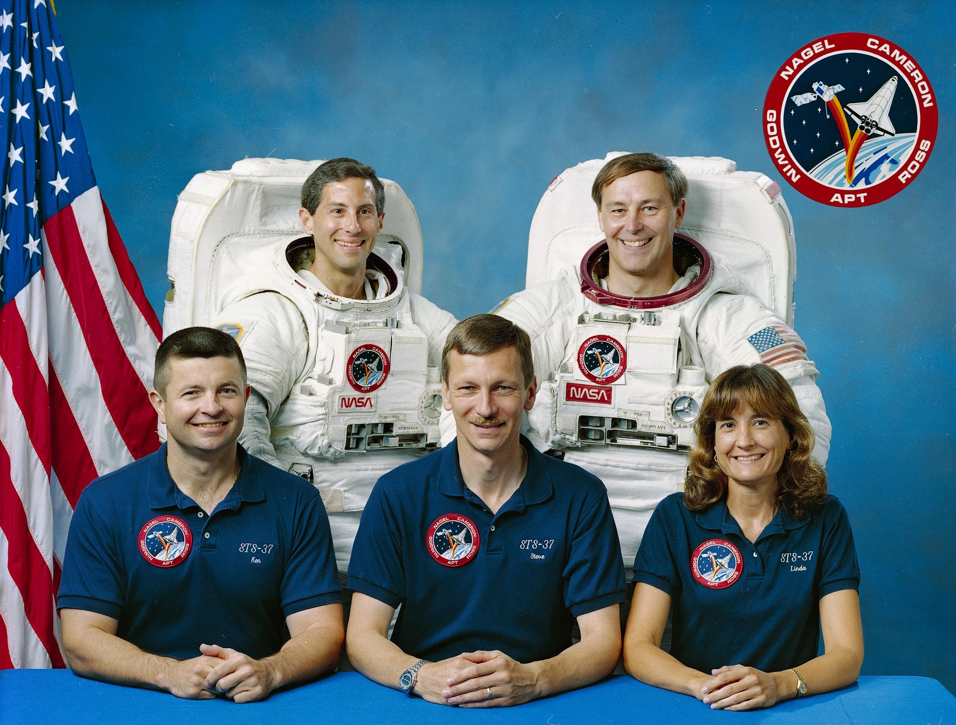 five crew members pose for crew portrait in front of US flag