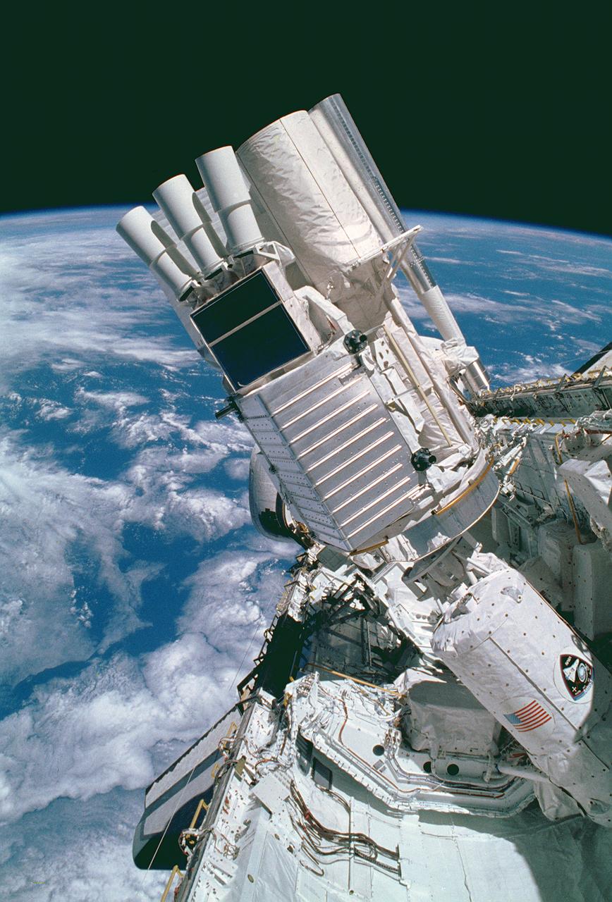 Onboard the Space Shuttle Orbiter Columbia (STS-35), the various components of the Astro-1 payload are seen backdropped against a blue and white Earth. Parts of the Hopkins Ultraviolet Telescope (HUT), the Ultraviolet Imaging Telescope (UIT), and the Wisconsin Ultraviolet Photo-Polarimetry Experiment (WUPPE) are visible on the Spacelab pallet. The Broad-Band X-Ray Telescope (BBXRT) is behind the pallet and is not visible in this scene. The smaller cylinder in the foreground is the igloo. The igloo was a pressurized container housing the Command Data Management System, that interfaced with the in-cabin controllers to control the Instrument Pointing System (IPS) and the telescopes. The Astro Observatory was designed to explore the universe by observing and measuring the ultraviolet radiation from celestial objects. Astronomical targets of observation selected for Astro missions included planets, stars, star clusters, galaxies, clusters of galaxies, quasars, remnants of exploded stars (supernovae), clouds of gas and dust (nebulae), and the interstellar medium. Managed by the Marshall Space Flight Center, the Astro-1 was launched aboard the Space Shuttle Orbiter Columbia (STS-35) on December 2, 1990.