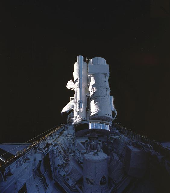 Onboard the Space Shuttle Orbiter Columbia (STS-35), the various components of the Astro-1 payload are seen backdropped against dark space. Parts of the Hopkins Ultraviolet Telescope (HUT), Ultraviolet Imaging Telescope (UIT), and the Wisconsin Ultraviolet Photo-Polarimetry Experiment (WUPPE) are visible on the Spacelab pallet. The Broad-Band X-Ray Telescope (BBXRT) is behind the pallet and is not visible in this scene. The smaller cylinder in the foreground is the igloo. The igloo was a pressurized container housing the Command Data Management System, that interfaced with the in-cabin controllers to control the Instrument Pointing System (IPS) and the telescopes. The Astro Observatory was designed to explore the universe by observing and measuring the ultraviolet radiation from celestial objects. Astronomical targets of observation selected for Astro missions included planets, stars, star clusters, galaxies, clusters of galaxies, quasars, remnants of exploded stars (supernovae), clouds of gas and dust (nebulae), and the interstellar medium. Managed by the Marshall Space Flight Center, the Astro-1 was launched aboard the Space Shuttle Orbiter Columbia (STS-35) on December 2, 1990.
