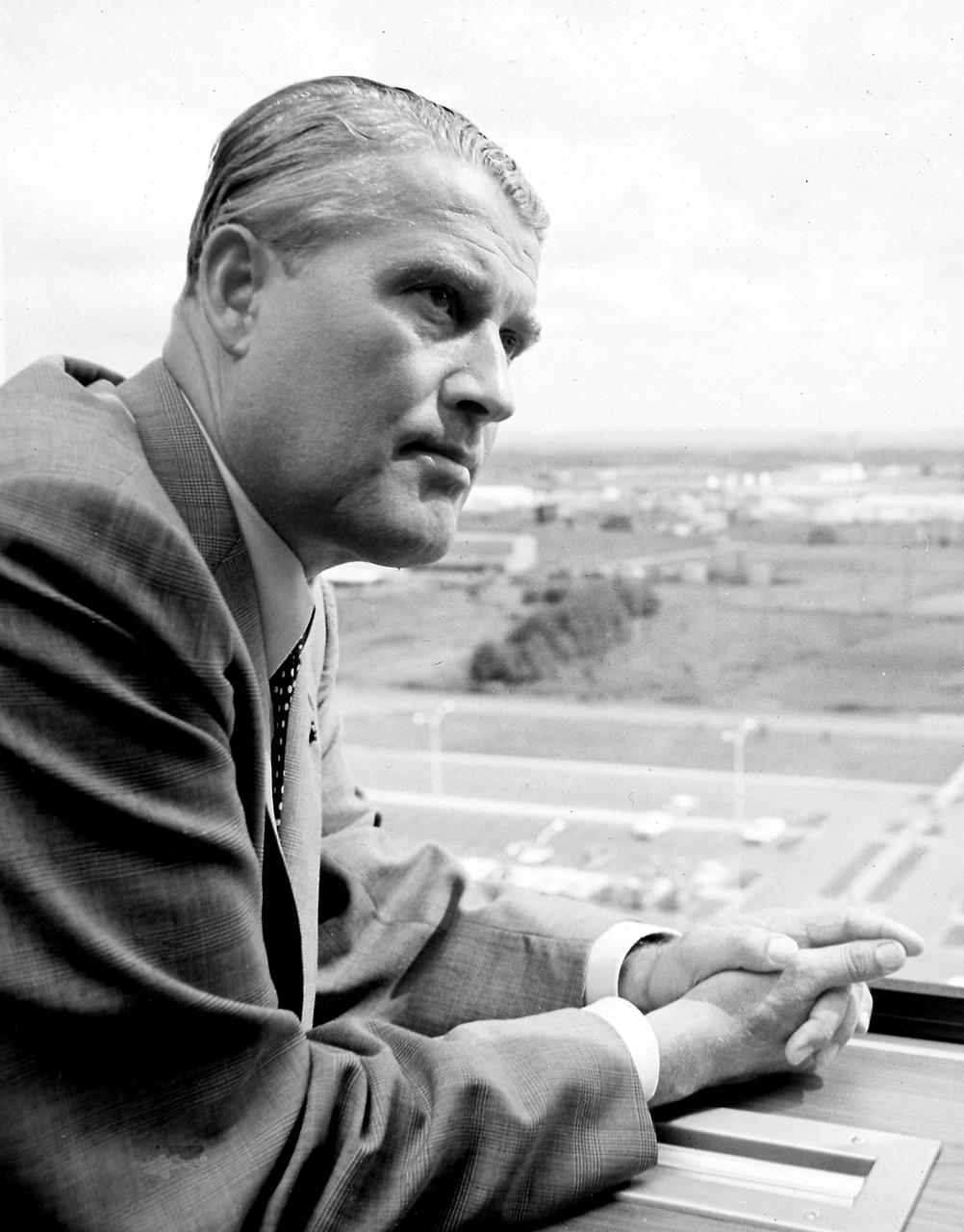 Dr. von Braun is looking out from a 10th floor window of building 4200 at the Marshall Space Flight Center (MSFC). He was the first Center Director and served as the Director from July 1960 through February 1970. Following World War II, Dr. von Braun and his German colleagues arrived in the United States under the Project Paperclip (American acquisition of German rocket experts) to continue their rocket development work. In 1950, von Braun and his German Rocket Team (also called the Peenemuende Team) were transferred from Ft. Bliss, Texas to Huntsville, Alabama to work for the Army's rocket program at Redstone Arsenal and later, NASA's Marshall Space Flight Center (MSFC). Under Dr. von Braun's leadership, MSFC developed the Saturn V launch vehicle, which placed the first men, two American astronauts, on the Moon. Wernher von Braun's life was dedicated to expanding man's knowledge through the exploration of space. 