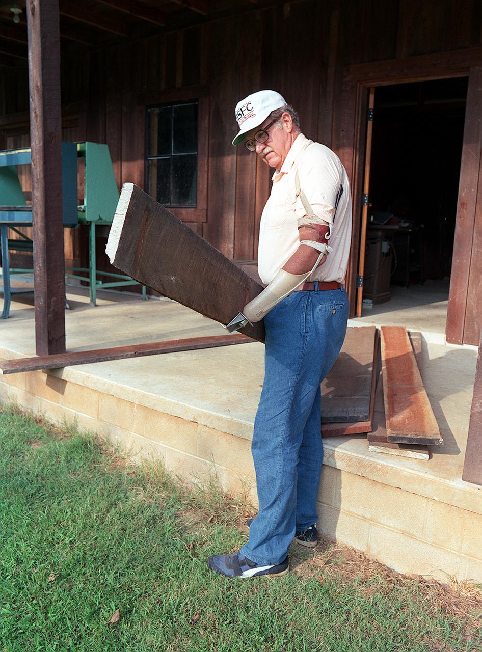 In this photograph, James Carden uses a NASA-developed prosthesis to moved planks around his home. Derived from foam insulation technology used to protect the Space Shuttle External Tank from excessive heat, FAB/CAD, a subsidiary of the Harshberger Prosthetic and Orthotic Center, utilized the technology to replace the heavy, fragile plaster they used to produce master molds for prosthetics. The new material was lighter, cheaper and easier to manufacture than plaster, resulting in lower costs to the customer.