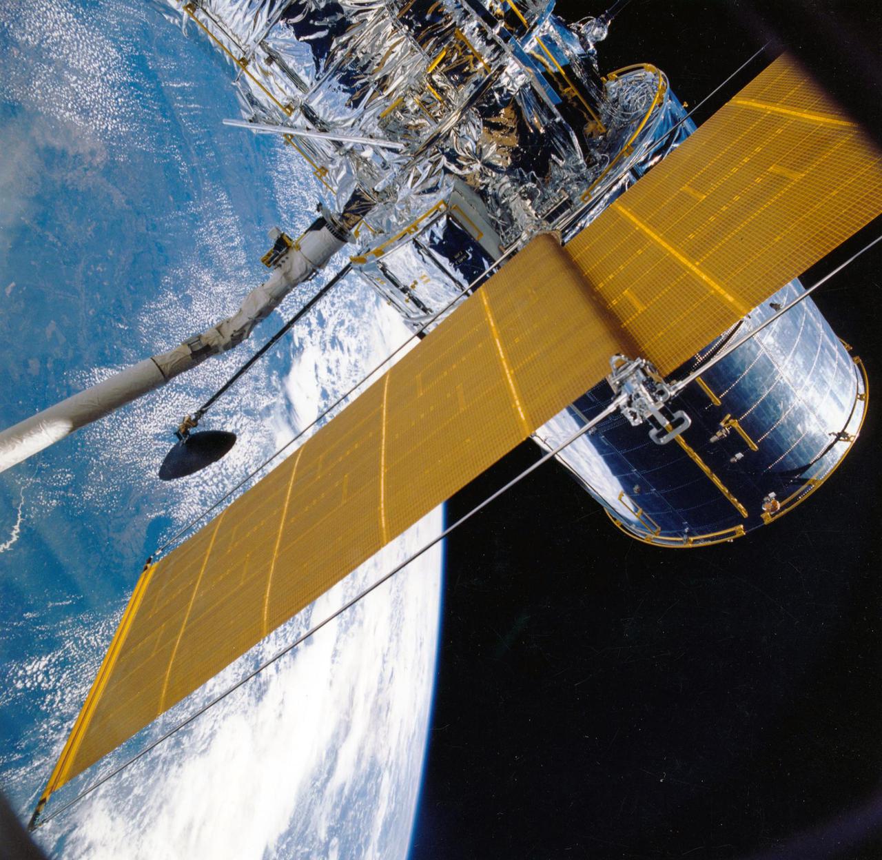 JOHNSON SPACE CENTER, HOUSTON, TEXAS -- STS-31 ONBOARD SCENE -- Most of the giant Hubble Space Telescope (HST) can be seen as it is suspended in space by Discovery's remote manipulator system (RMS), following the deployment of part of its solar panels and antennae.  The photo was taken with a handheld Hasselblad camera. This was among the first photos NASA released on April 30 from the five-day STS-31 mission.
