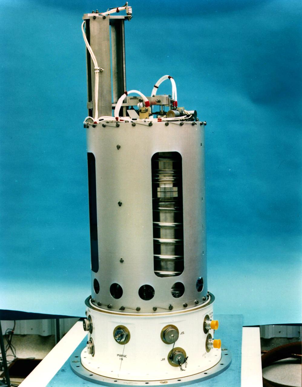 The Advanced Automated Directional Solidification Furnace (AADSF) with the Experimental Apparatus Container (EAC) removed flew during the USMP-2 mission. During USMP-2, the AADSF was used to study the growth of mercury cadmium telluride crystals in microgravity by directional solidification, a process commonly used on earth to process metals and grow crystals. The furnace is tubular and has three independently controlled temperature zones . The sample travels from the hot zone of the furnace (1600 degrees F) where the material solidifies as it cools. The solidification region, known as the solid/liquid interface, moves from one end of the sample to the other at a controlled rate, thus the term directional solidification.