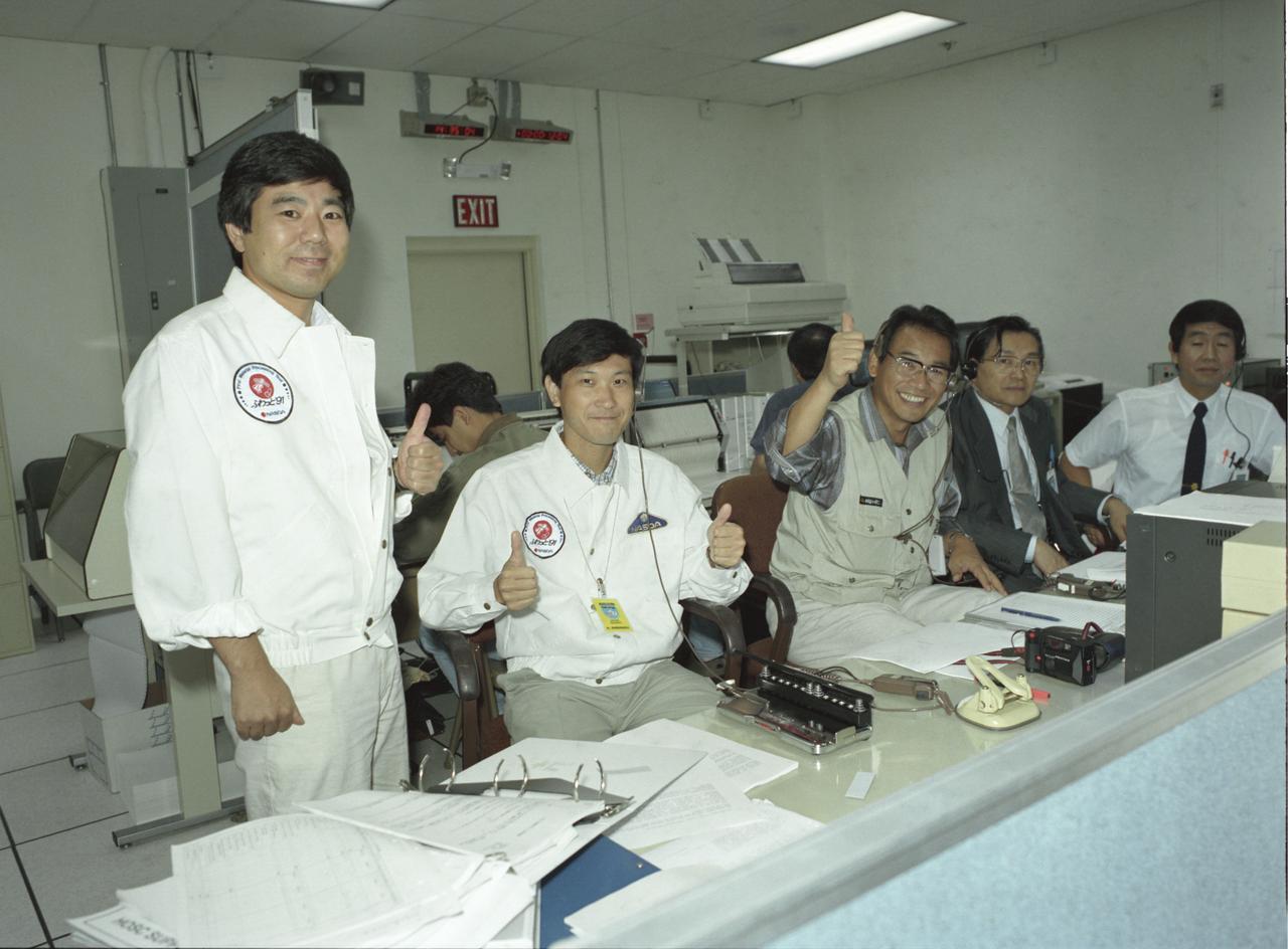 The group of Japanese researchers of the Spacelab-J (SL-J) were thumbs-up in the Payload Operations Control Center (POCC) at the Marshall Space Flight Center after the successful launch of Space Shuttle Orbiter Endeavour that carried their experiments. The SL-J was a joint mission of NASA and the National Space Development Agency of Japan (NASDA) utilizing a marned Spacelab module. The mission conducted microgravity investigations in materials and life sciences. Materials science investigations covered such fields as biotechnology, electronic materials, fluid dynamics and transport phenomena, glasses and ceramics, metals and alloys, and acceleration measurements. Life sciences included experiments on human health, cell separation and biology, developmental biology, animal and human physiology and behavior, space radiation, and biological rhythms. Test subjects included the crew, Japanese koi fish (carp), cultured animal and plant cells, chicken embryos, fruit flies, fungi and plant seeds, frogs, and frog eggs. The POCC was the air/ground communications channel between the astronauts and ground control teams during the Spacelab missions. The Spacelab science operations were a cooperative effort between the science astronaut crew in orbit and their colleagues in the POCC. Spacelab-J was launched aboard the Space Shuttle Orbiter Endeavour on September 12, 1992.