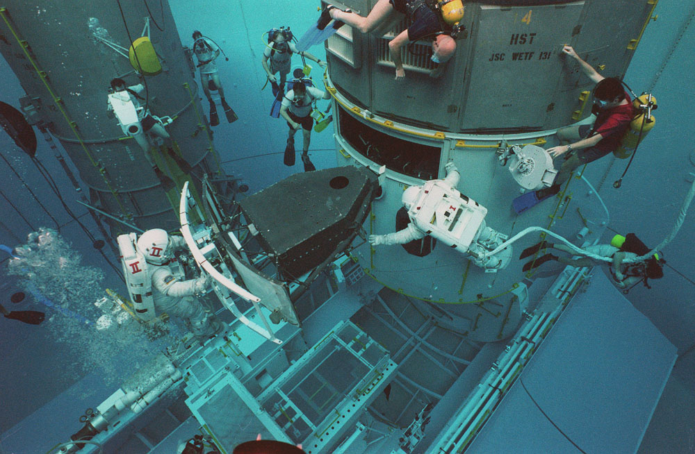 Two astronauts practice installing an instrument into the Hubble Space Telescope at Marshall's Neutral Buoyancy Simulator.