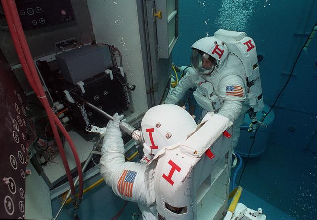 Astronauts Kathy Thornton and Tom Akers practice installing the Wide Field Planetary camera into the Hubble Space Telescope at Marshall's Neutral Buoyancy Simulator (NBS).