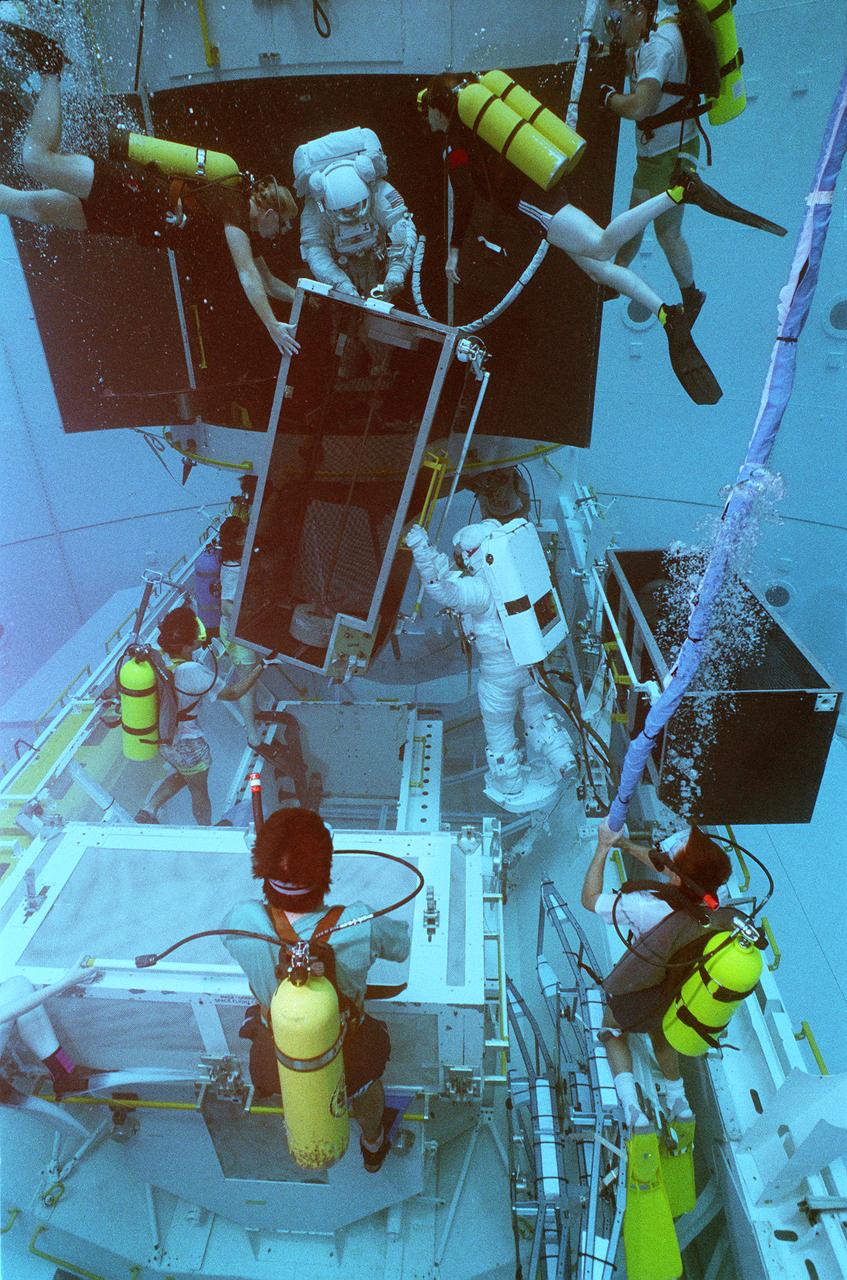 This photograph shows STS-61 crewmemmbers training for the Hubble Space Telescope (HST) servicing mission in the Marshall Space Flight Center's (MSFC's) Neutral Buoyancy Simulator (NBS). Two months after its deployment in space, scientists detected a 2-micron spherical aberration in the primary mirror of the HST that affected the telescope's ability to focus faint light sources into a precise point. This imperfection was very slight, one-fiftieth of the width of a human hair. A scheduled Space Service servicing mission (STS-61) in 1993 permitted scientists to correct the problem. The MSFC NBS provided an excellent environment for testing hardware to examine how it would operate in space and for evaluating techniques for space construction and spacecraft servicing.