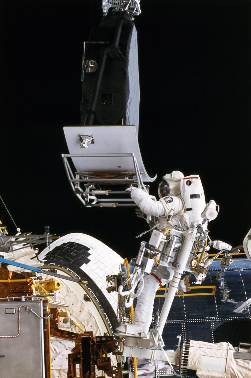 Astronaut Hoffman held the Hubble Space Telescope (HST) Wide Field/Planetary Camera-1 (WF/PC1) that was replaced by WF/PC2 in the cargo bay of the Space Shuttle orbiter Endeavour during Extravehicular Activity (EVA). The STS-61 mission was the first of the series of the HST servicing missions. Two months after its deployment in space, scientists detected a 2-micron spherical aberration in the primary mirror of the HST that affected the telescope's ability to focus faint light sources into a precise point. This imperfection was very slight, one-fiftieth of the width of a human hair. During four spacewalks, the STS-61 crew replaced the solar panel with its flexing problems; the WF/PC1 with WF/PC2, with built-in corrective optics; and the High-Speed Photometer with the Corrective Optics Space Telescope Axial Replacement (COSTAR) to correct the aberration for the remaining instruments. The purpose of the HST, the most complex and sensitive optical telescope ever made, is to study the cosmos from a low-Earth orbit for 15 years or more. The HST provides fine detail imaging, produces ultraviolet images and spectra, and detects very faint objects. The Marshall Space Flight Center had responsibility for design, development, and construction of the HST. The Perkin-Elmer Corporation, in Danbury, Cornecticut, developed the optical system and guidance sensors.