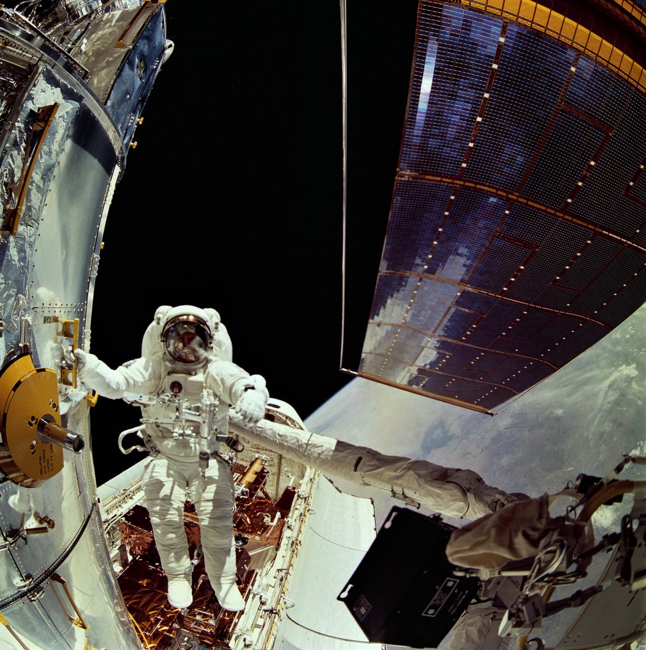 This is a Space Shuttle mission STS-61 onboard view showing astronauts Story Musgrave and Jeffrey Hoffman preforming repairs to the Hubble Space Telescope (HST) during their Extra Vehicular Activity (EVA). Astronauts' work was made easier by the HST's many crew aids. Astronaut Musgrave makes use of one of the spacecraft's handholds. Launched on December 1, 1993, the Space Shuttle Orbiter Endeavor STS-061 mission was the 59th Shuttle flight.