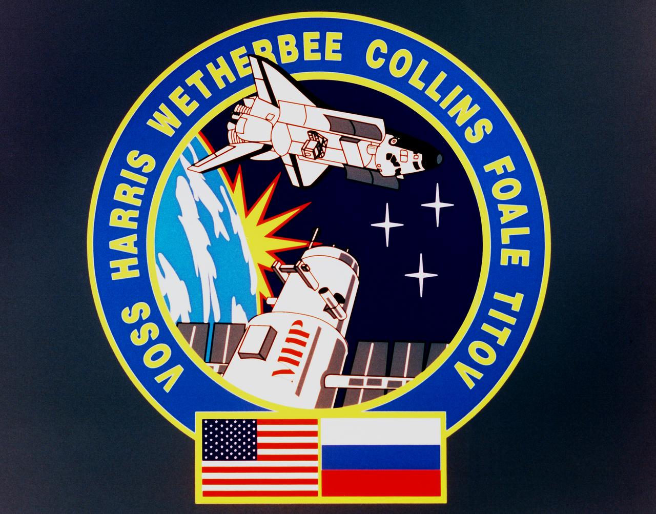 Designed by the crew members, the STS-63 crew patch depicts the orbiter maneuvering to rendezvous with Russia's Space Station Mir. The name is printed in Cyrillic on the side of the station. Visible in the Orbiter's payload bay are the commercial space laboratory Spacehab and the Shuttle Pointed Autonomous Research Tool for Astronomy (SPARTAN) satellite which are major payloads on the flight. The six points on the rising sun and the three stars are symbolic of the mission's Space Transportation System (STS) numerical designation. Flags of the United States and Russia at the bottom of the patch symbolize the cooperative operations of this mission. 