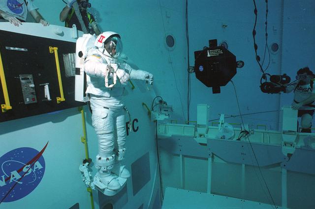 A diver tests a secondary camera and maneuvering platform in Marshall's Neutral Buoyancy Simulator (NBS).The secondary camera will be beneficial for recording repairs and other extra vehicular activities (EVA) the astronuats will perform while making repairs on the Hubble Space Telescope (HST). The maneuvering platform was developed to give the astronauts something to stand on while performing maintenance tasks. These platforms were developed to be mobile so that the astronauts could move them to accommadate different sites.