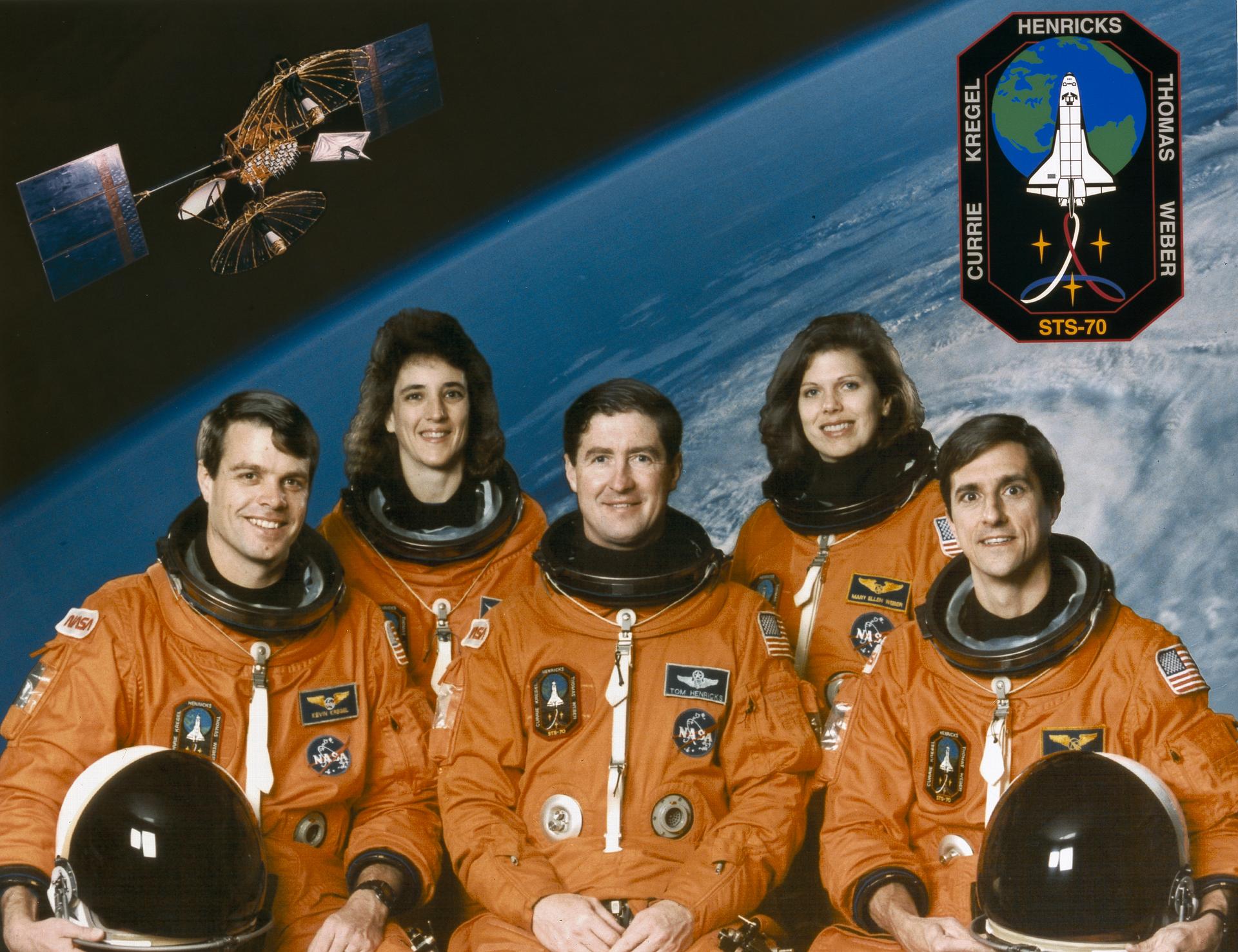 Three men and two women in orange spacesuits pose for crew photo.