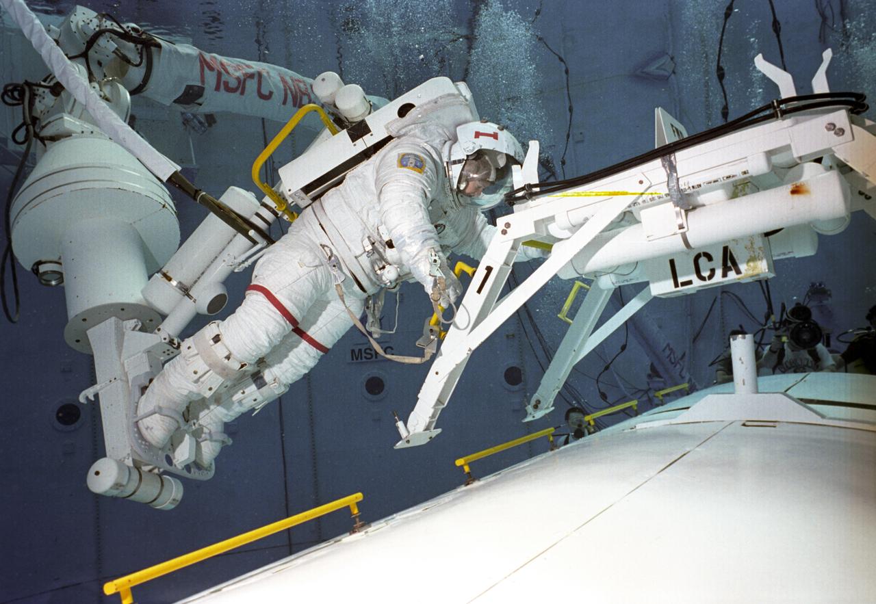 Astronauts Susan Helms (#1) and Carl Walz (#2) are training in the Neutral Buoyancy Simulator (NBS) at Marshall Space Flight center with an exercise for International Space Station Alpha. The NBS provided the weightless environment encountered in space needed for testing and the practices of Extravehicular Activities (EVA).