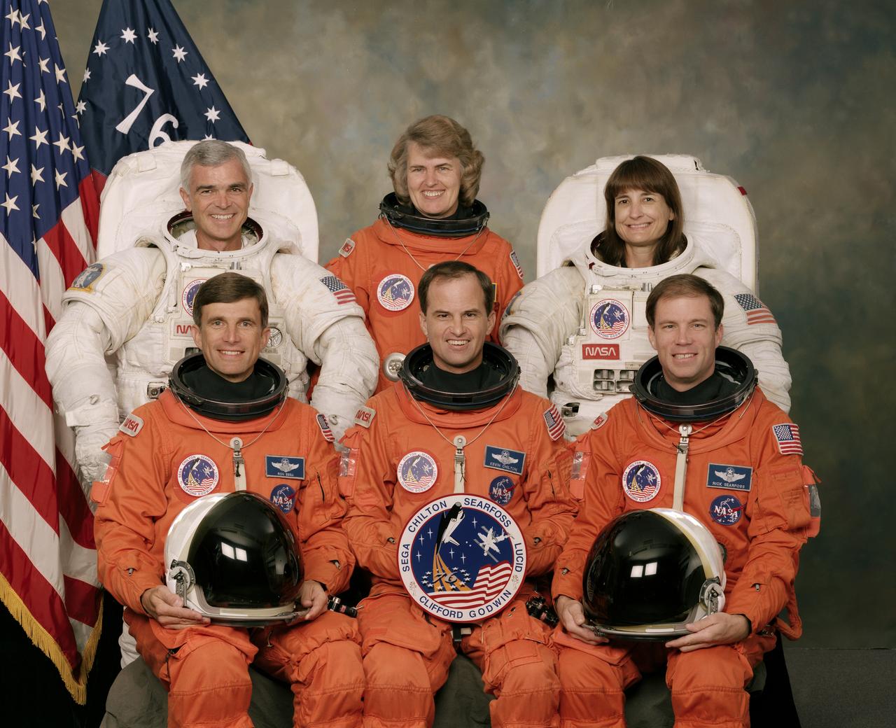 These six NASA astronauts launched into space aboard the Space Shuttle Atlantis on March 22, 1996 for the STS-76 mission. Pictured on the front row, left to right, are astronauts Ronald M. Sega, mission specialist; Kevin P. Chilton, mission commander; and Richard A. Searfoss, pilot. On the back row, left to right, are mission specialists Michael R. (Rich) Clifford, Shannon W. Lucid, and Linda M. Godwin. The third U.S. Shuttle-Mir docking, STS-76 began a new period of international cooperation in space exploration with the first Shuttle transport of a United States astronaut (Lucid) to Russia’s Mir Space Station for extended joint space research. Clifford and Godwin, pictured here in training versions of the Extravehicular Mobility Unit (EMU), performed the first Extravehicular Activity (EVA) during Mir-Shuttle docked operations. 