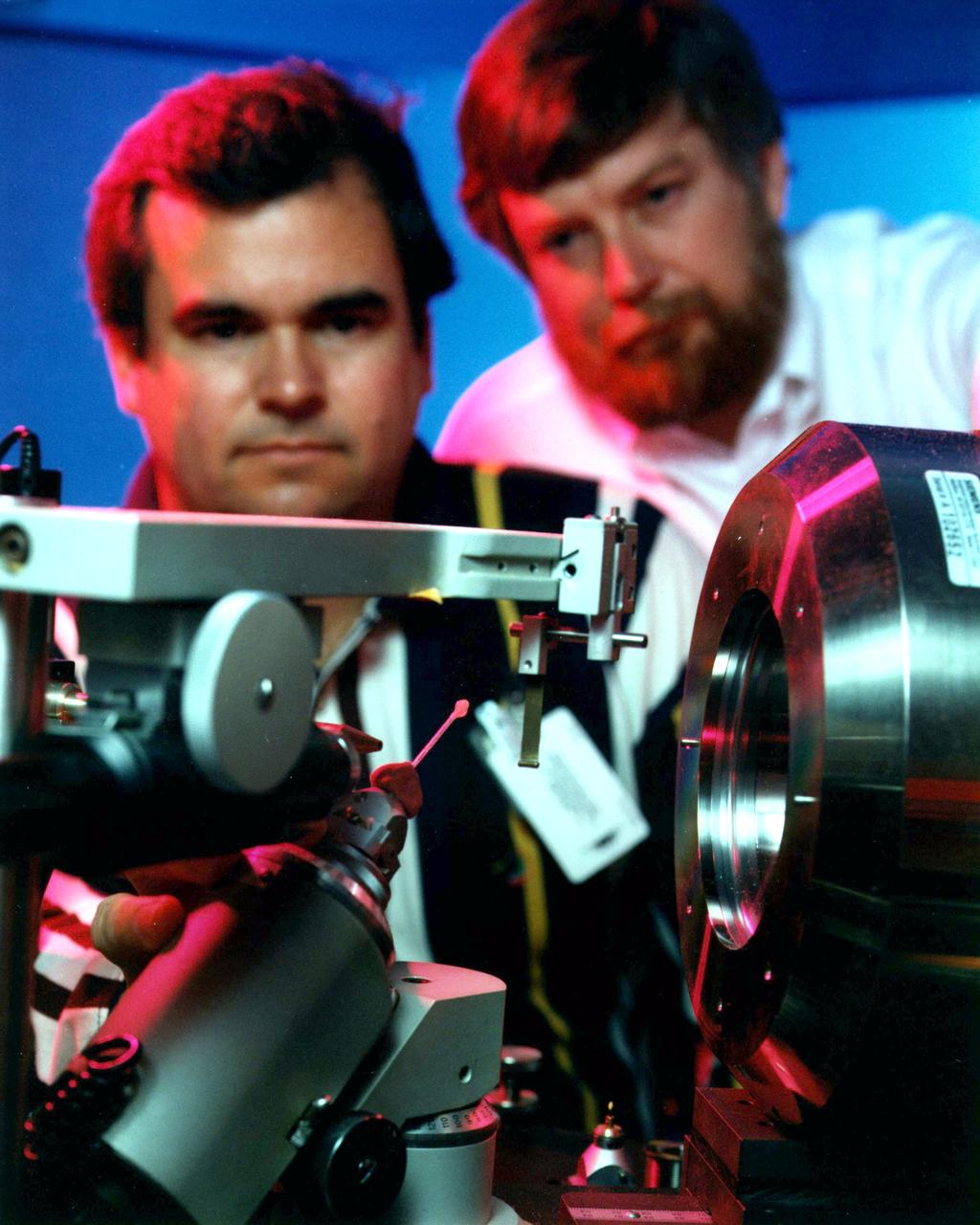 Dan Carter and Charles Sisk center a Lysozyme Protein crystal grown aboard the USML-2 shuttle mission. Protein isolated from hen egg-white and functions as a bacteriostatic enzyme by degrading bacterial cell walls. First enzyme ever characterized by protein crystallography. It is used as an excellent model system for better understanding parameters involved in microgravity crystal growth experiments. The goal is to compare kinetic data from microgravity experiments with data from laboratory experiments to study the equilibrium.